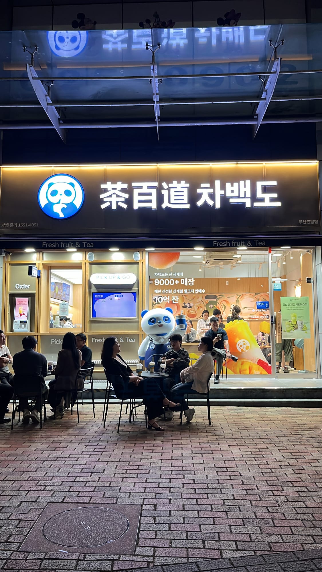 Storefront glass window with giant inflatable tea cup and business hours at ChaPanda Busan Centum