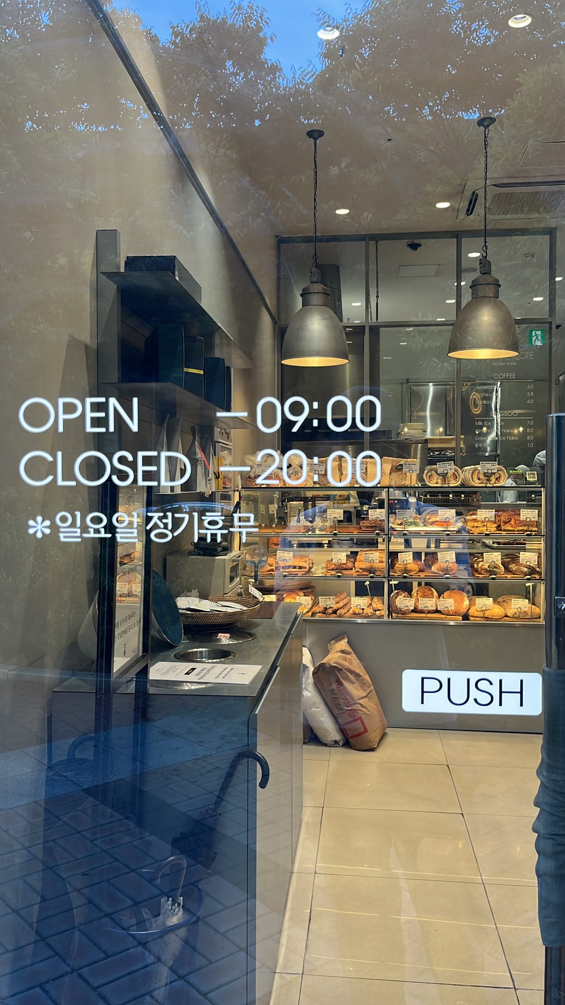 Glass door entrance showing operating hours at Ordinary Recipe Centum artisanal bakery