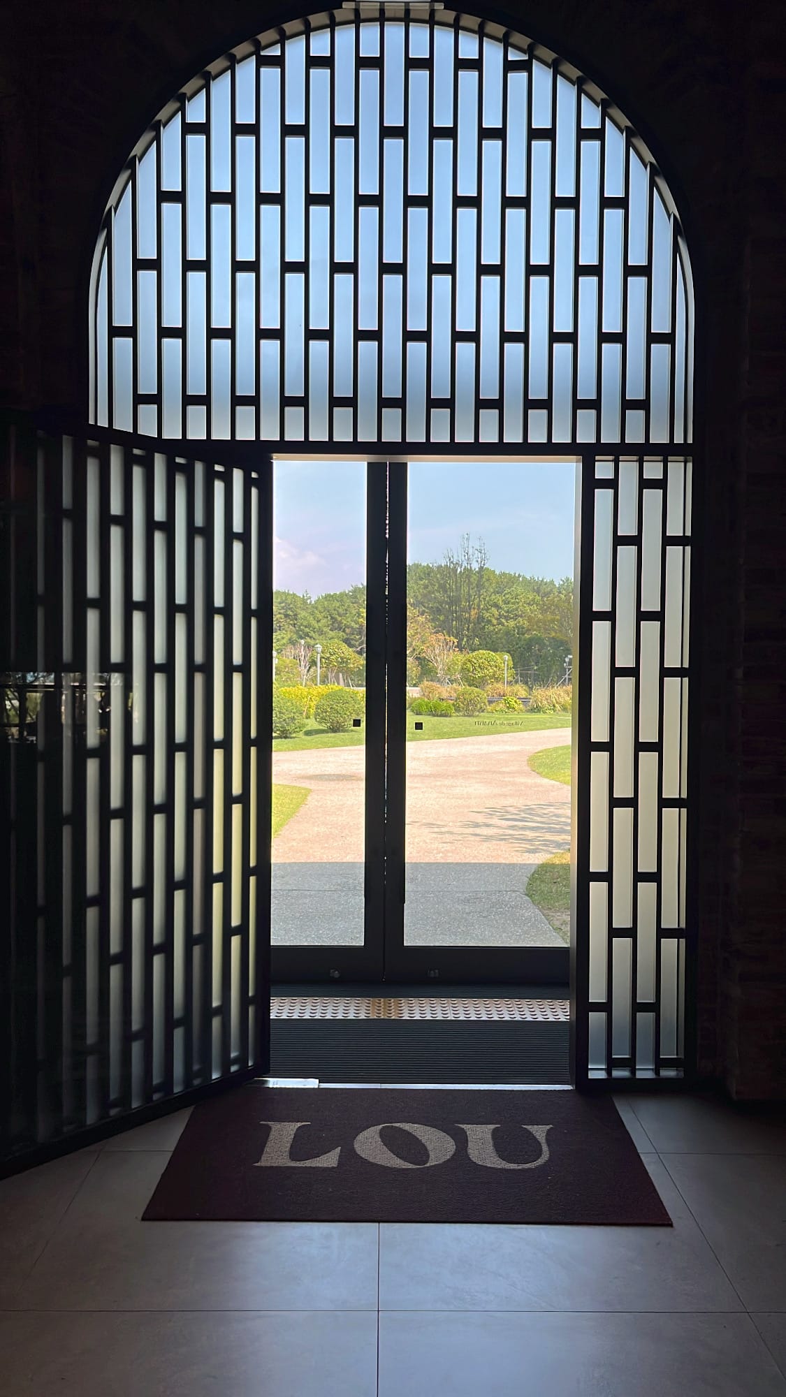 Impressive oriental arched entrance door opening to manicured outdoor grounds at Village de Ananti Lou Busan