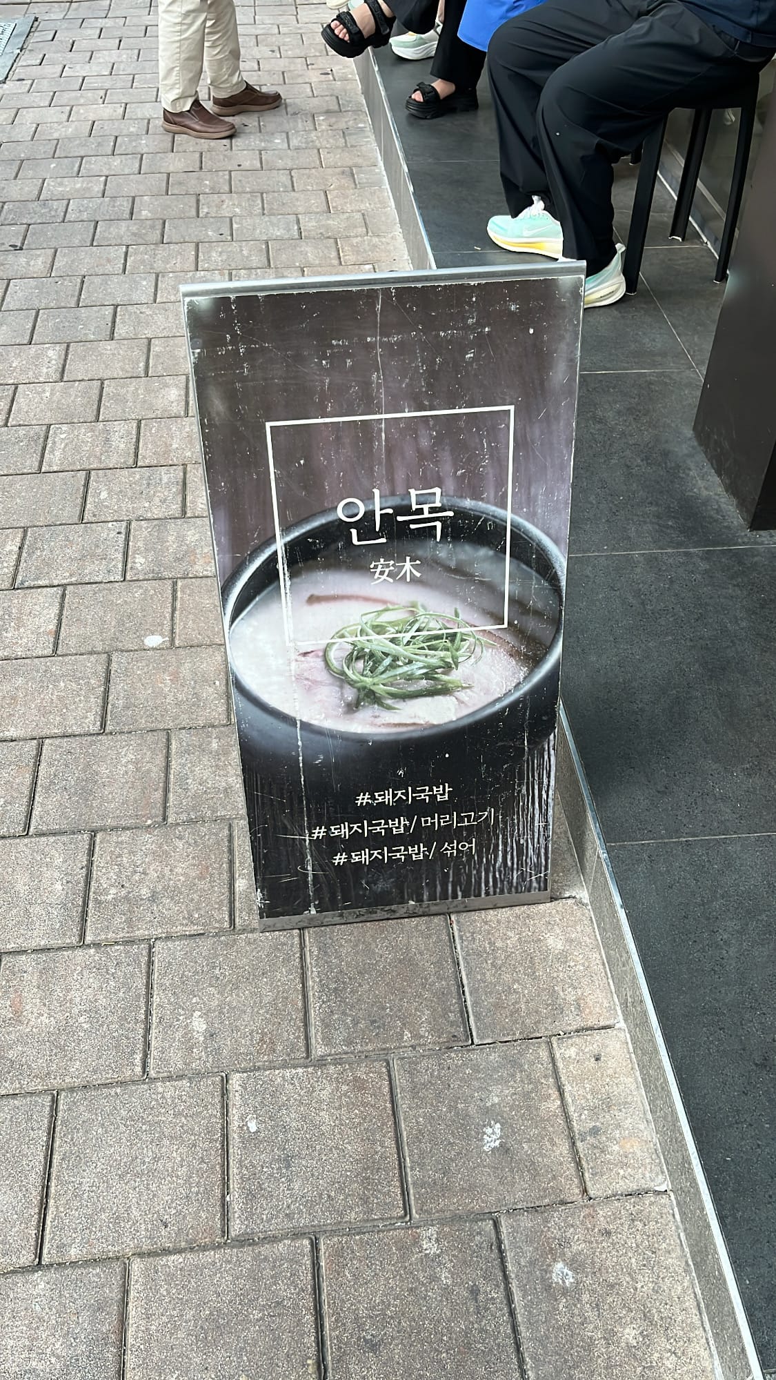 Street-level standing banner and sidewalk waiting line outside Anmok Busan