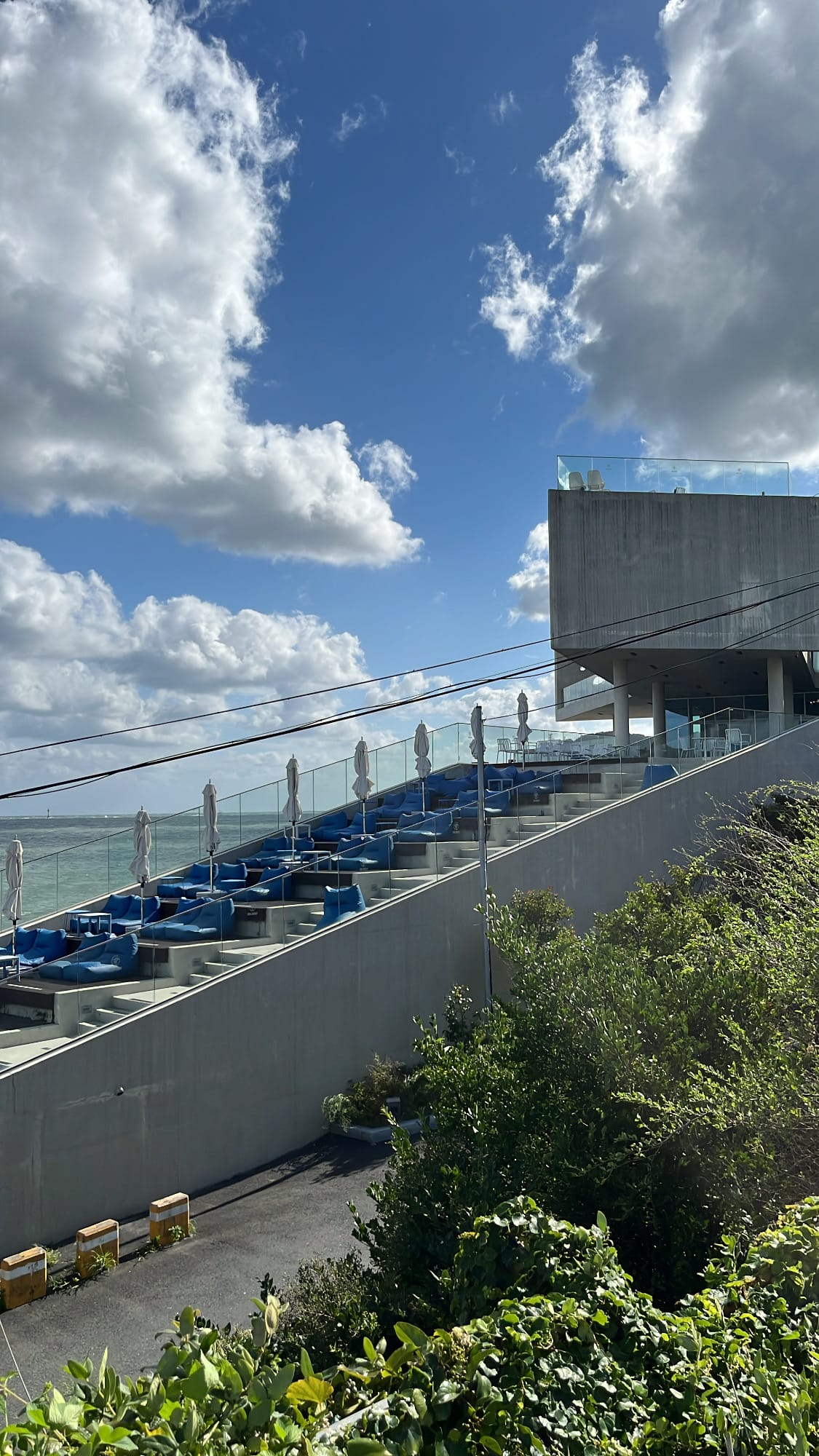 Outdoor tiered terrace with blue beanbag loungers facing the sea at Coralani Busan
