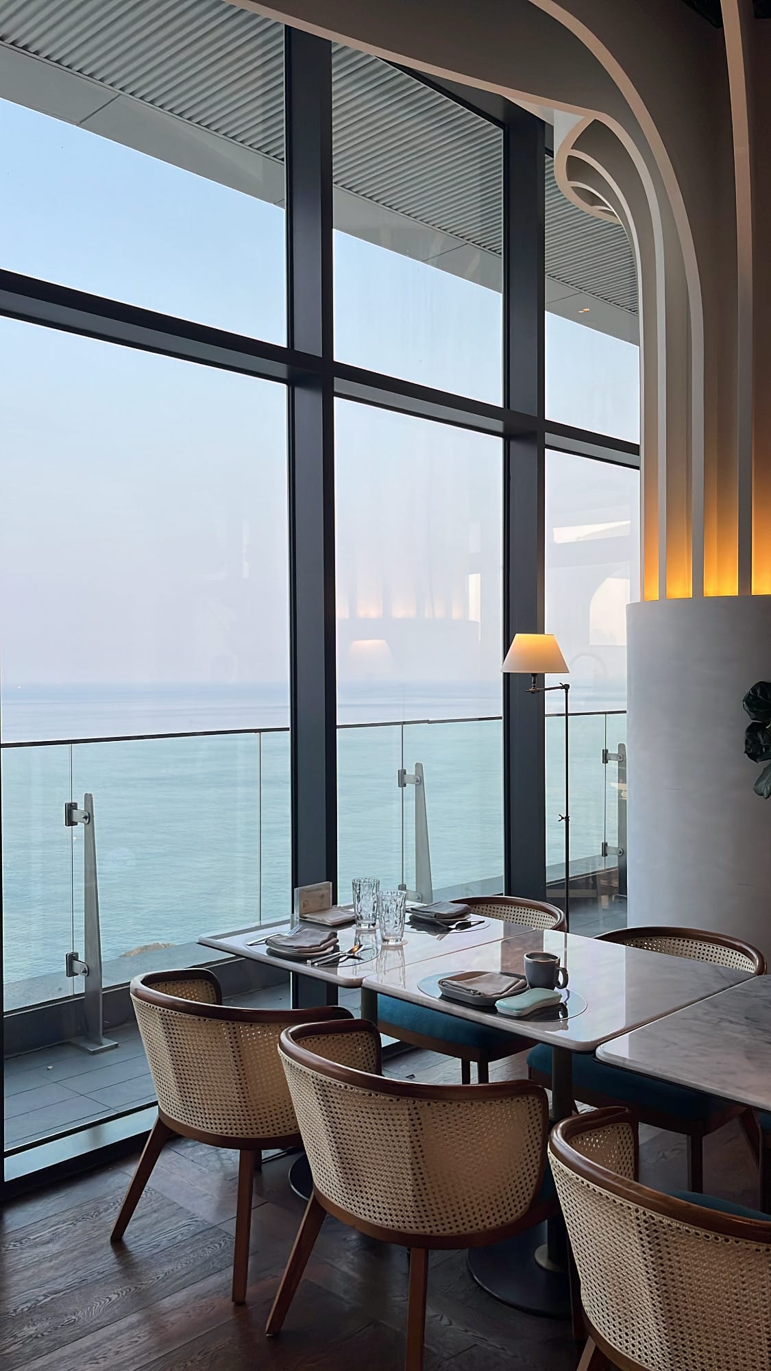Panoramic floor-to-ceiling ocean view window seating at McQueen's Grill and Bar