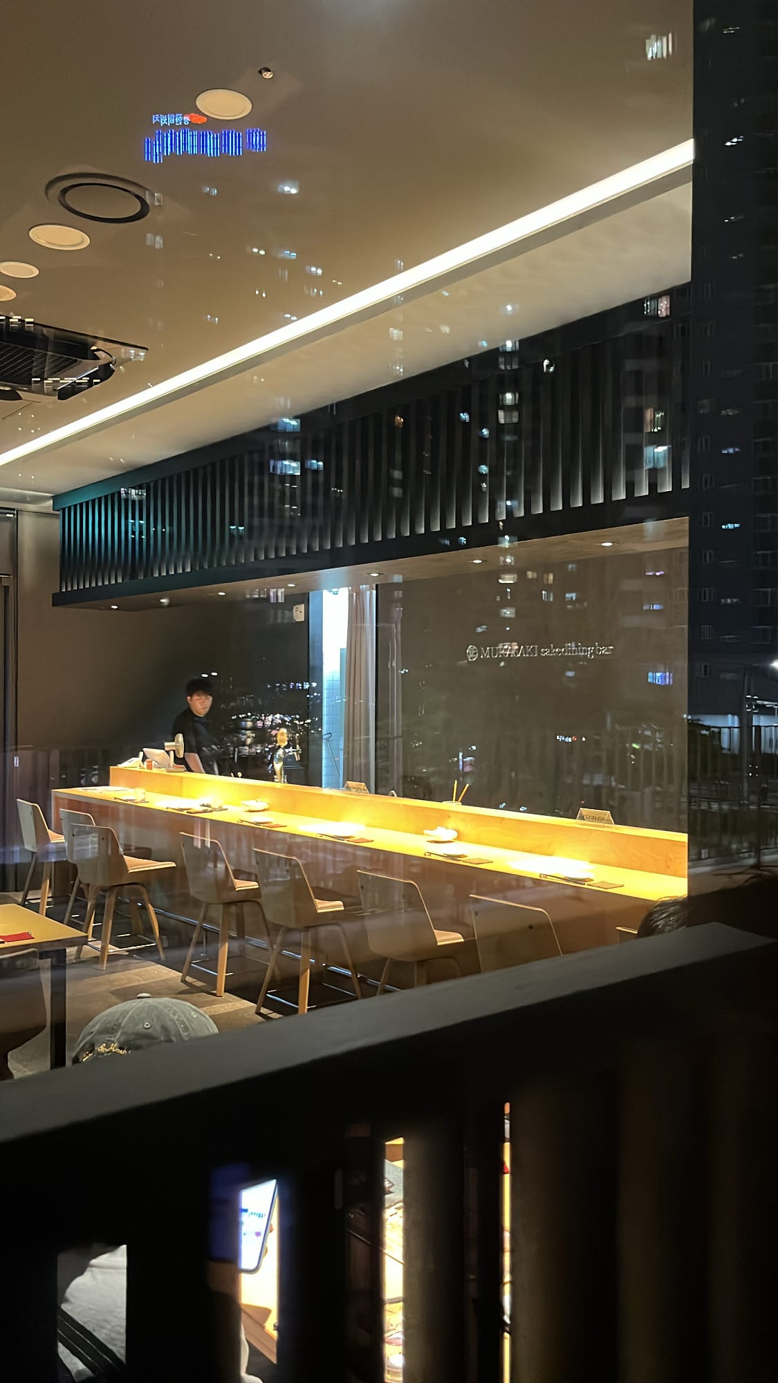 Counter seating and cozy lighting seen through the window at Murasaki Busan