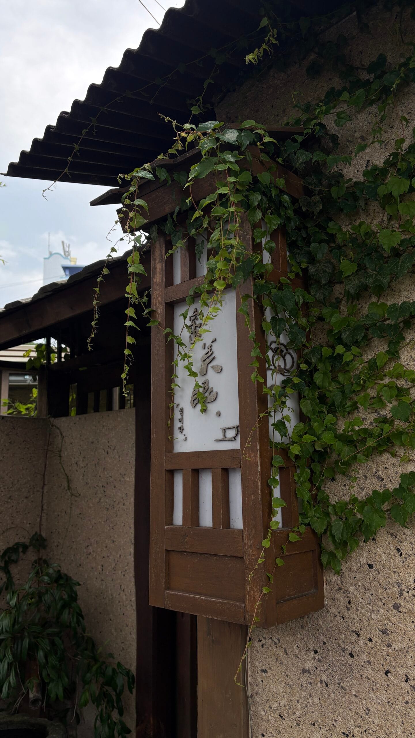 Traditional wooden lantern mounted on ivy-covered wall at Simmian Busan