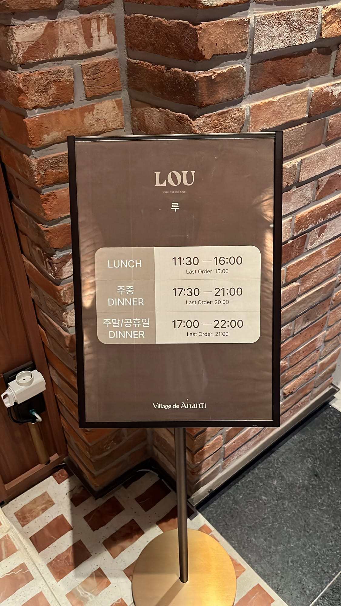 Sleek floor stand listing lunch and dinner operating hours at Village de Ananti Lou Busan