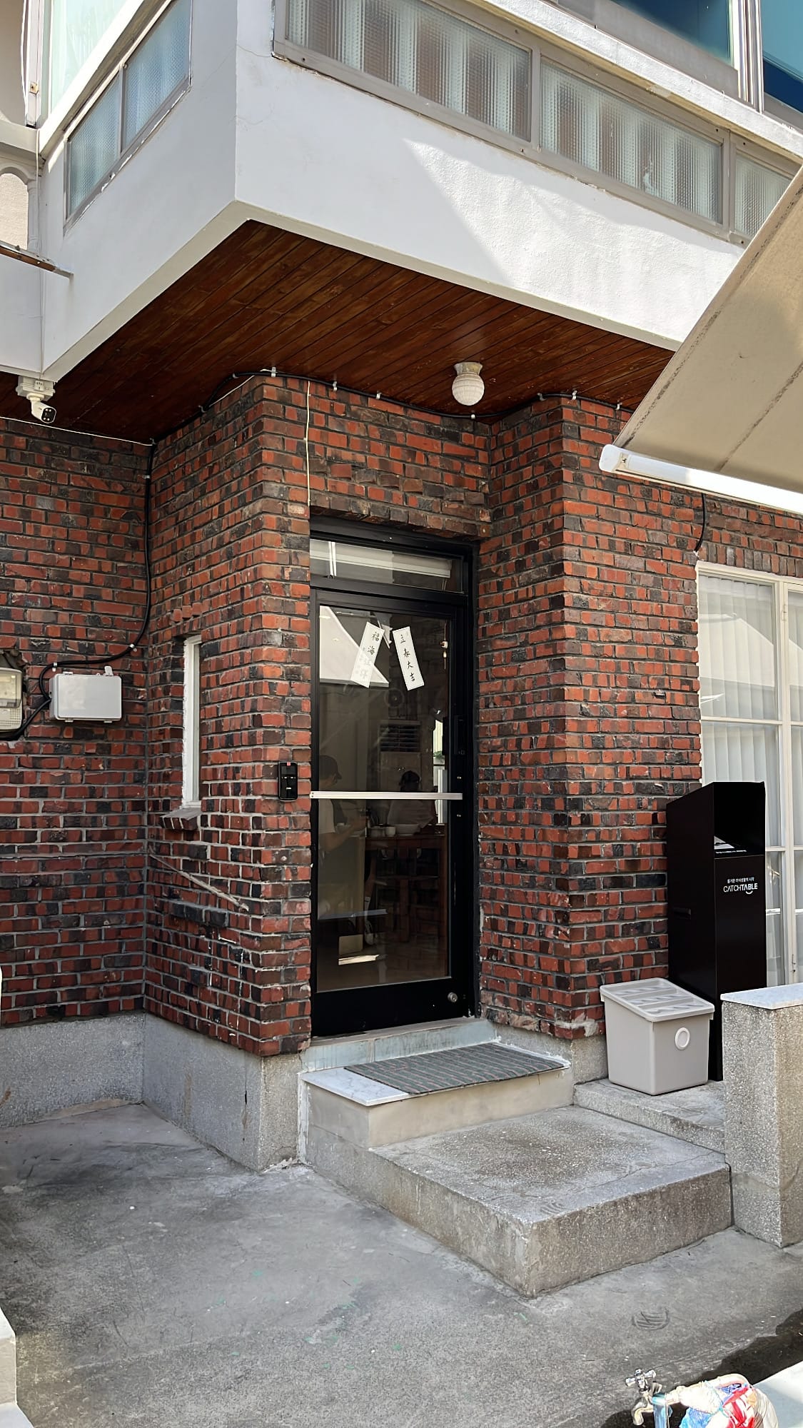 Red brick front entrance door and concrete steps of Yangkyungoak Busan