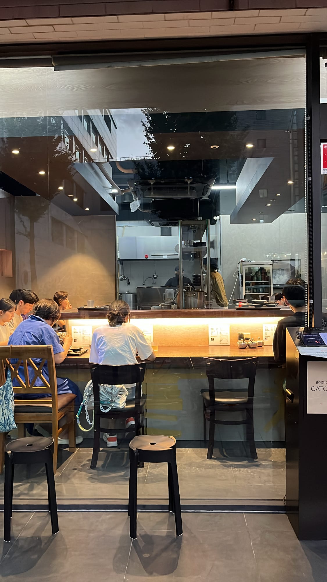 Transparent front glass window view showing the 16-seat bar counter dining room at Anmok Busan
