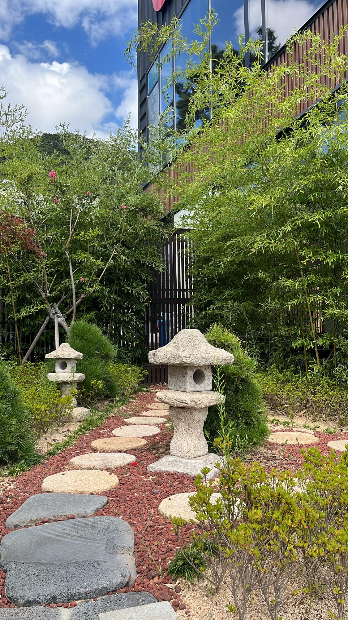 Traditional stone lanterns and lush bamboo garden walkway beside Unaju Busan