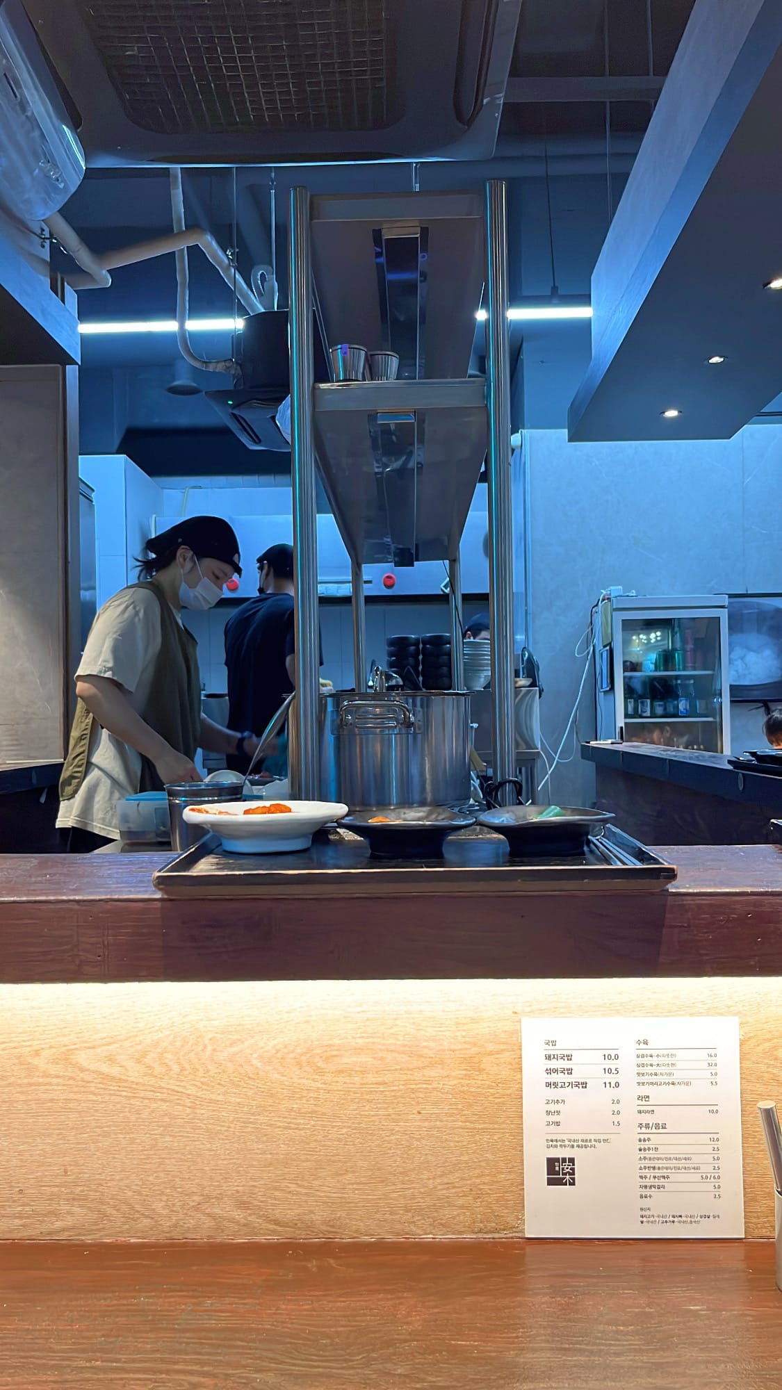 Open kitchen preparation counter where chefs assemble bowls of pork soup at Anmok Busan