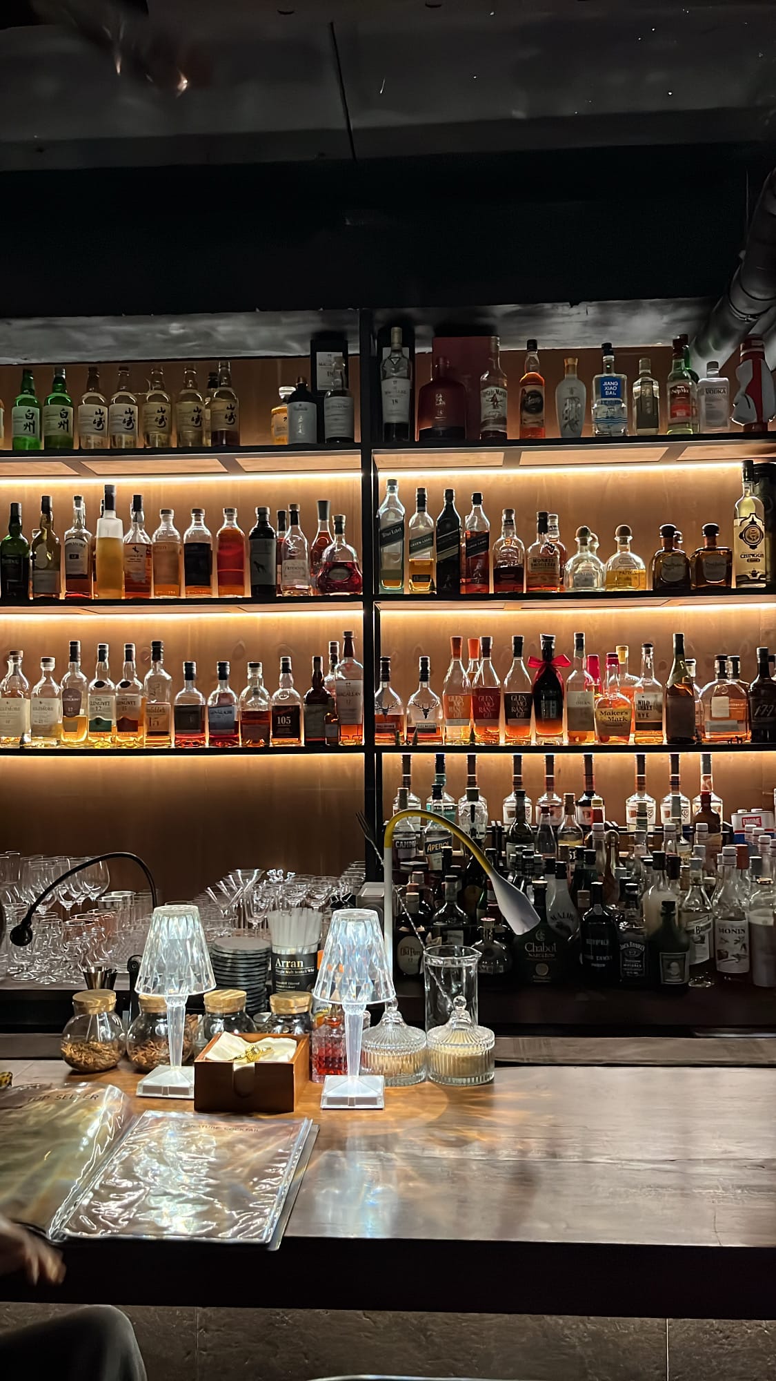 Multi-tier illuminated back bar stocked with spirits and whiskies