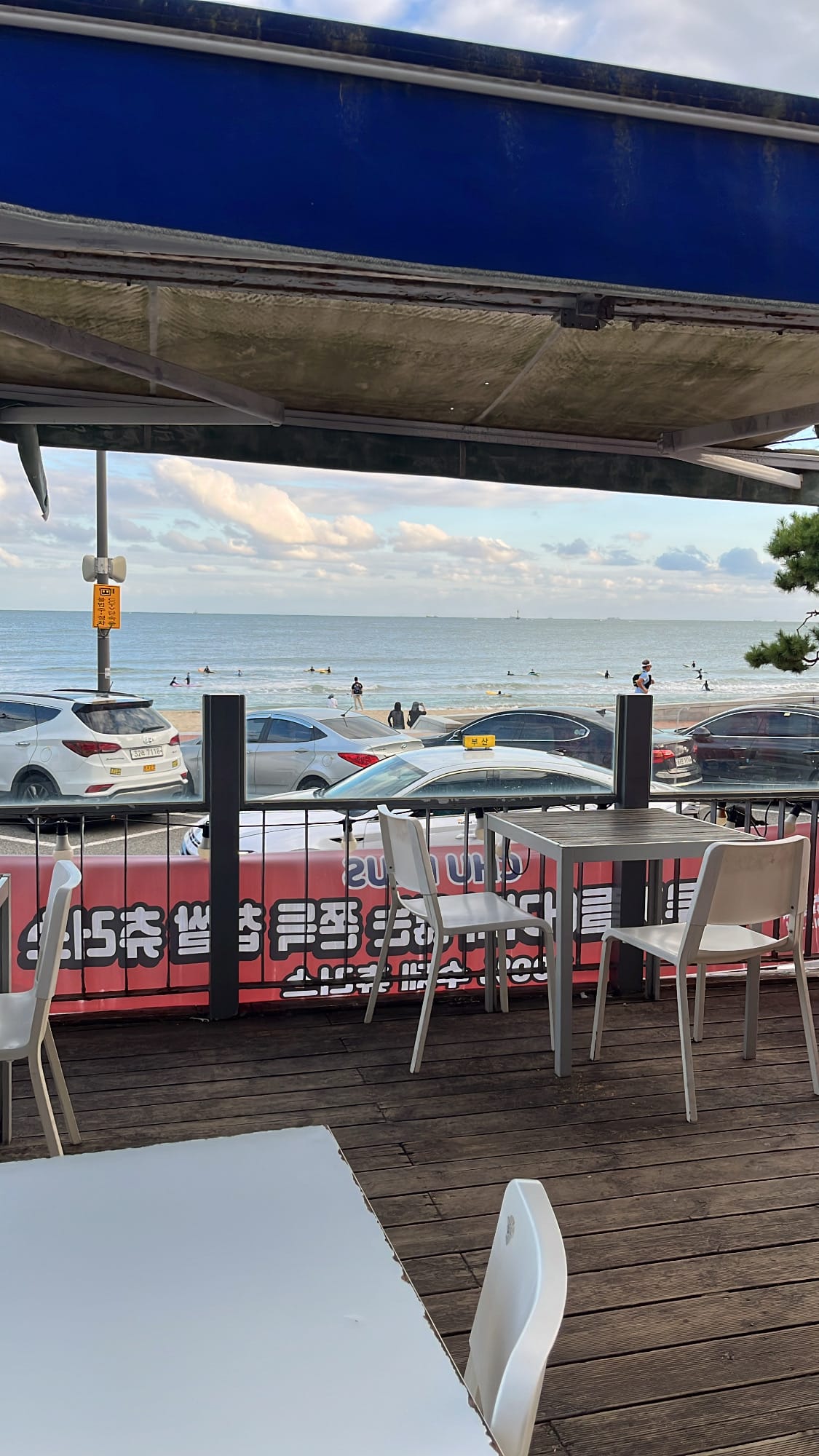 Covered outdoor wooden terrace seating with ocean view at Chuplus Songjeong Busan