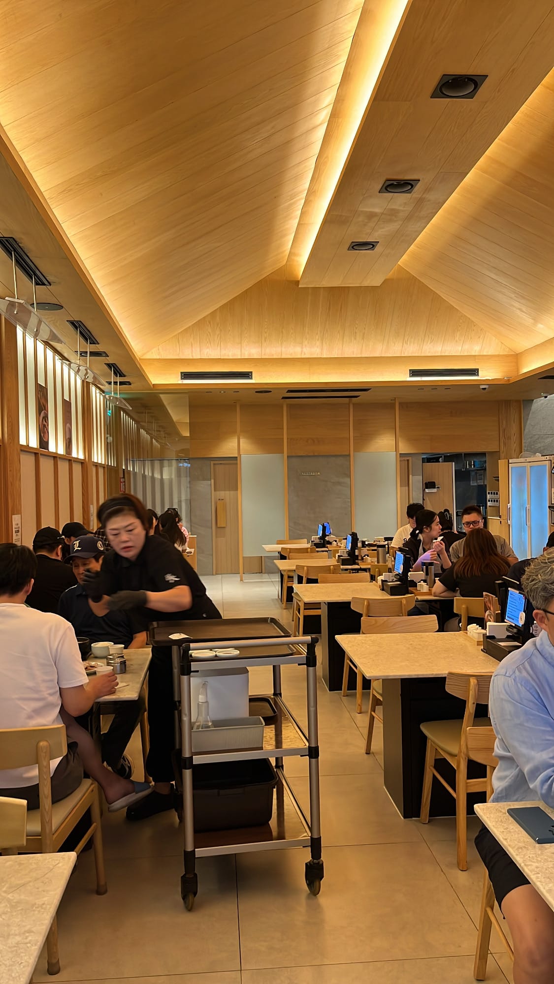 Bustling restaurant atmosphere with modern ceiling beams at Geodae Dwaeji Gukbap Busan