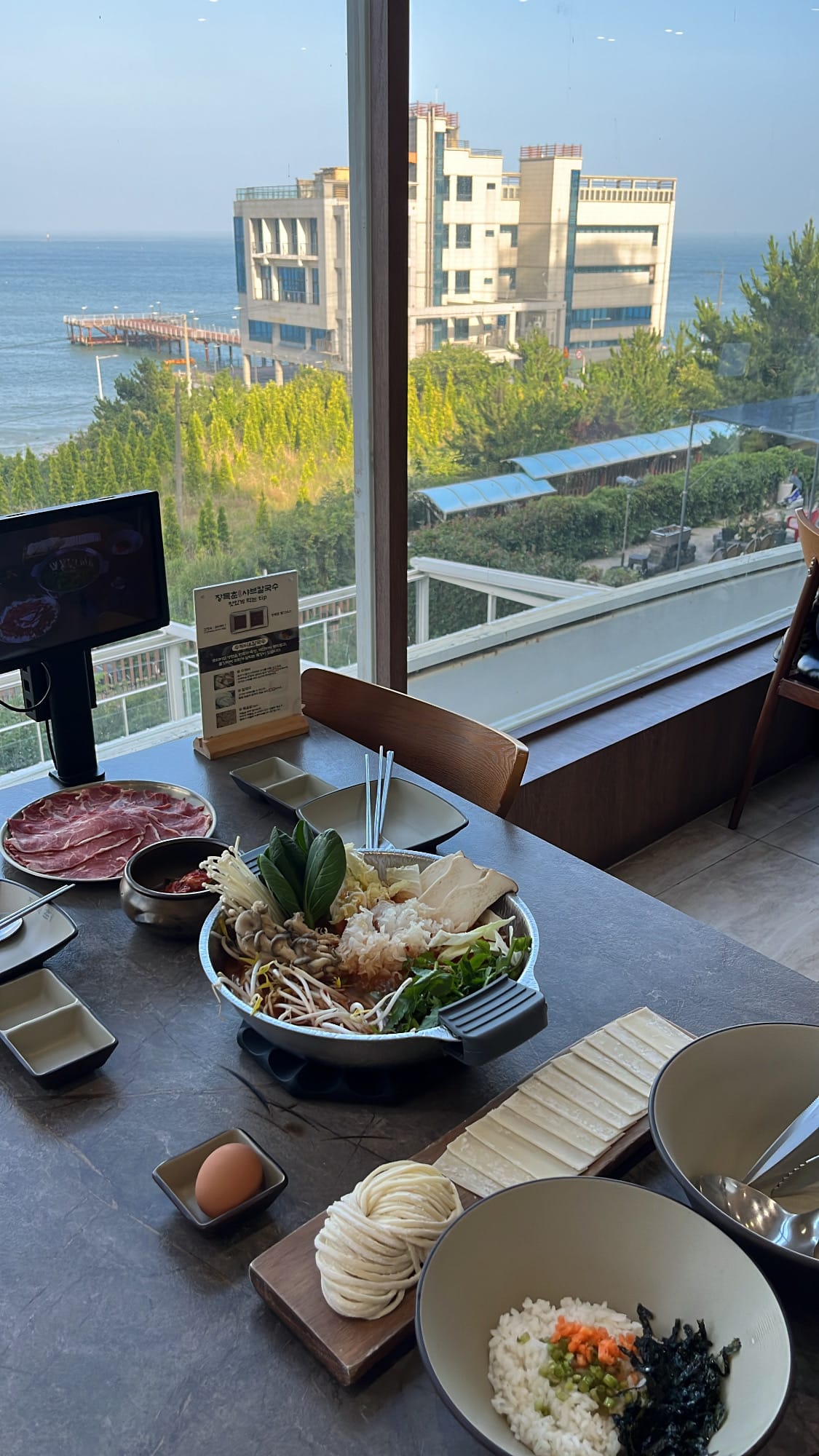 Generous 2-person shabu-shabu meal served by the window with Songjeong ocean view