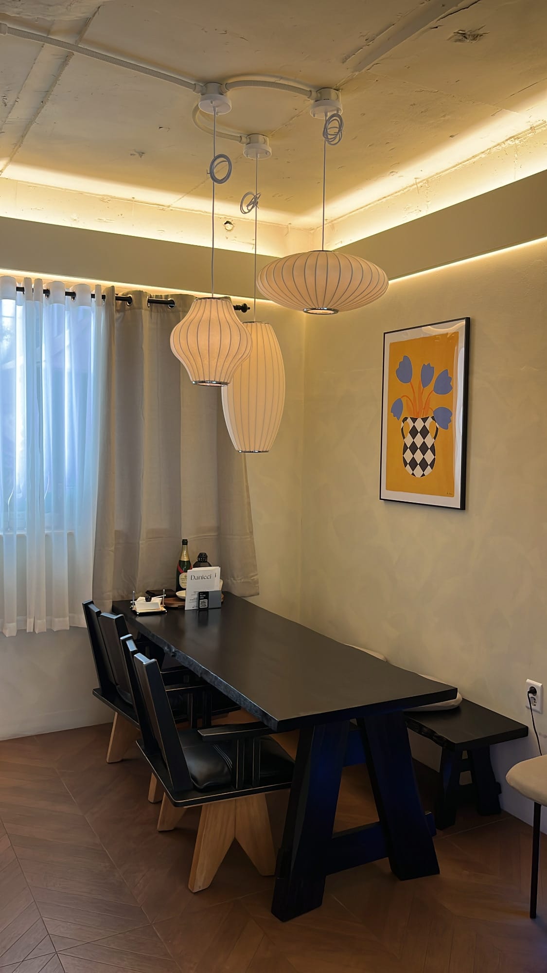Danicci private wooden table illuminated by pleated pendant lamps
