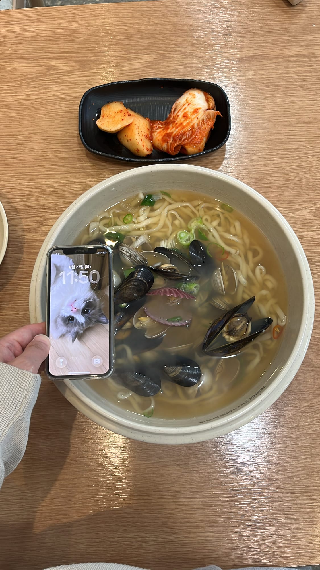Smartphone placed next to the giant 31cm seafood kalguksu bowl for scale