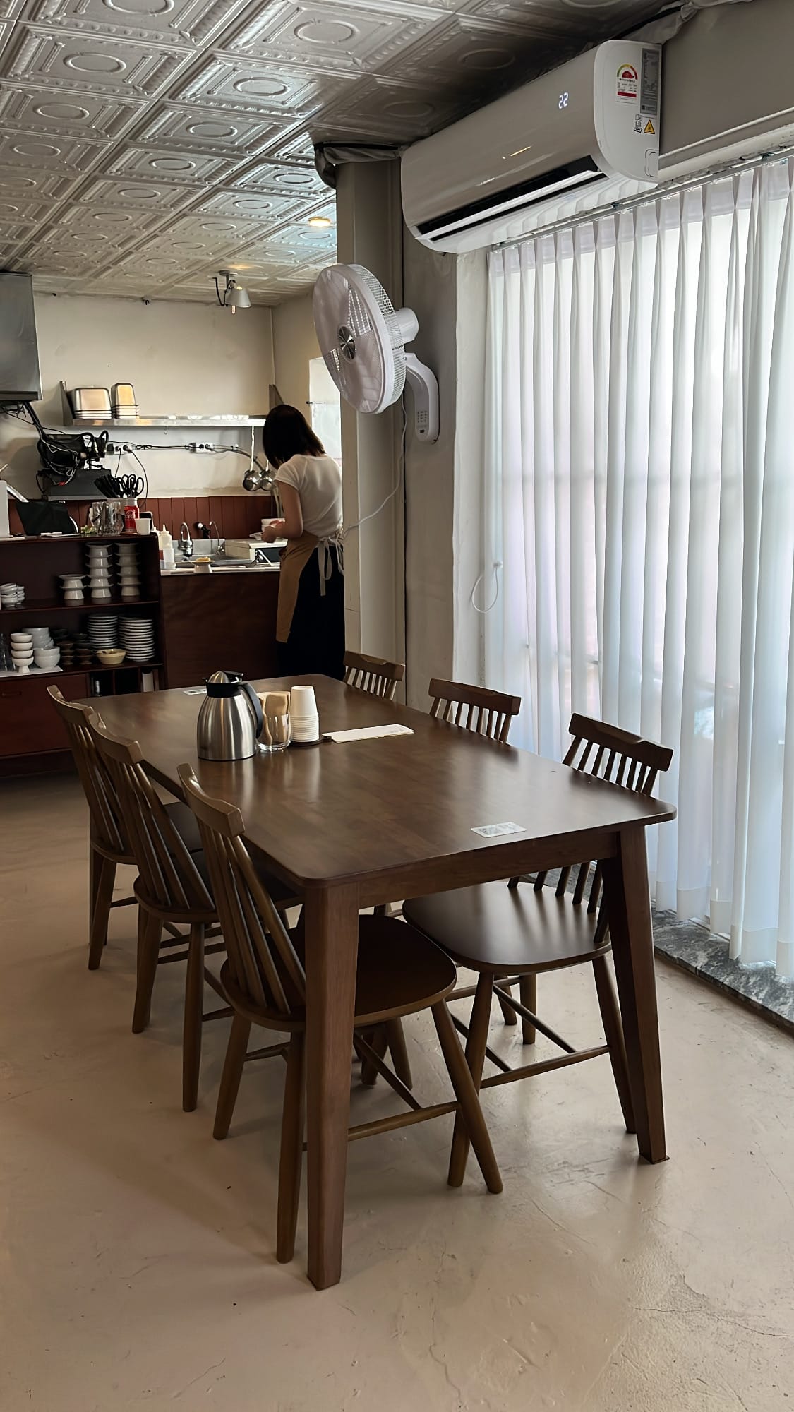 Four-person wooden dining table beside sheer white curtains at Yangkyungoak Busan