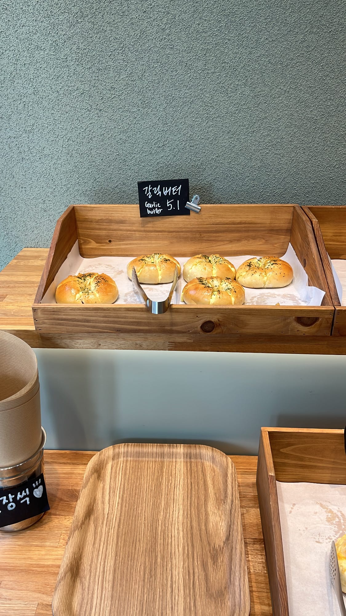 Fresh golden garlic butter bagels resting on bakery tray at Bagel Then You Busan Centum