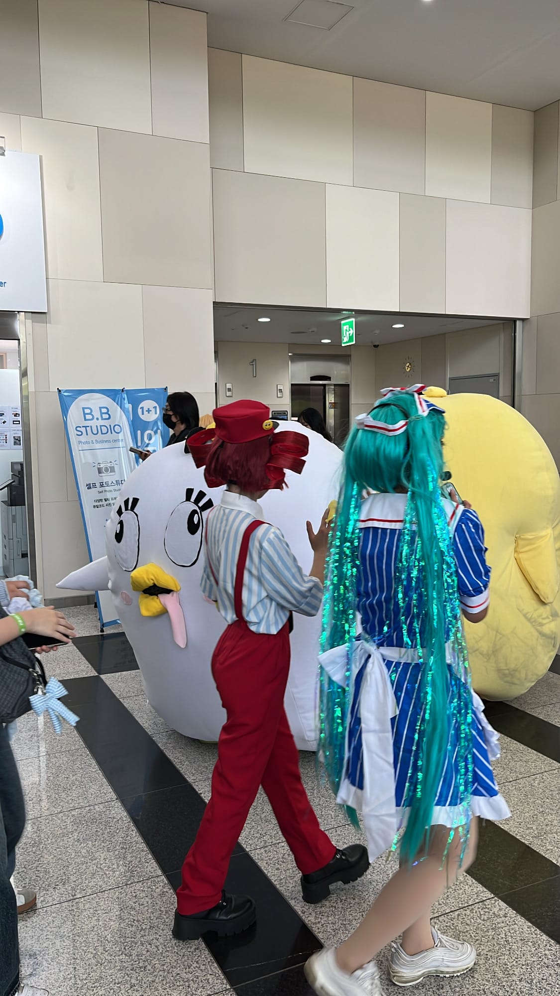 Hatsune Miku and oversized bird mascot walking in BEXCO lobby
