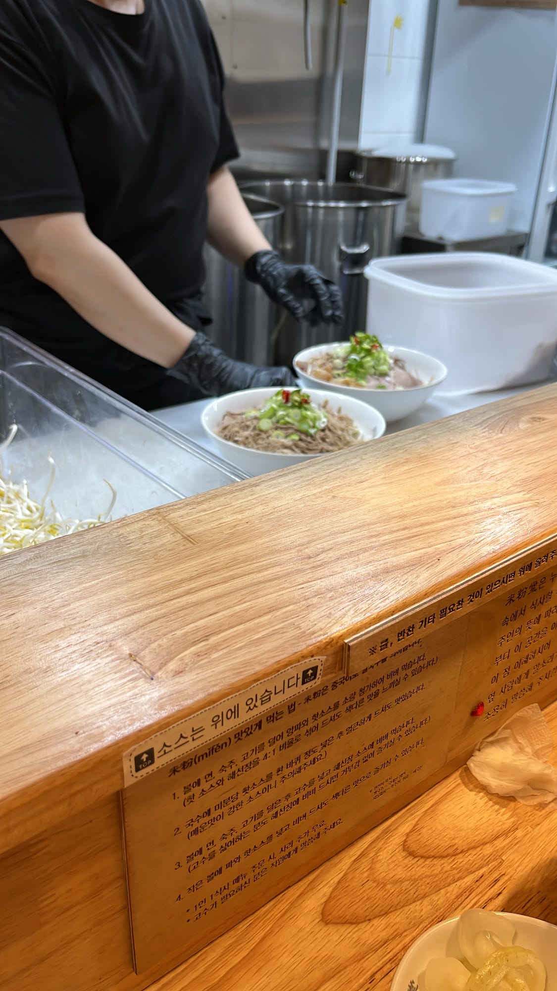 Chef preparing freshly assembled pho bowls in the open kitchen at Mibundang Centum City