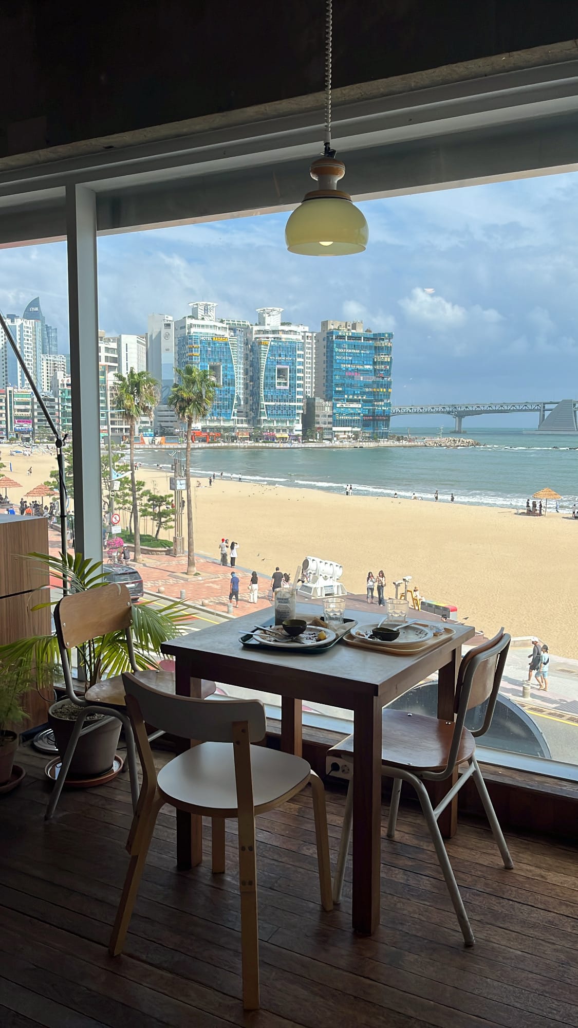โต๊ะริมหน้าต่างที่มองออกสู่ชายหาดกวังอัลลีอันสวยงาม ที่ Working Holiday Brunch Cafe Busan