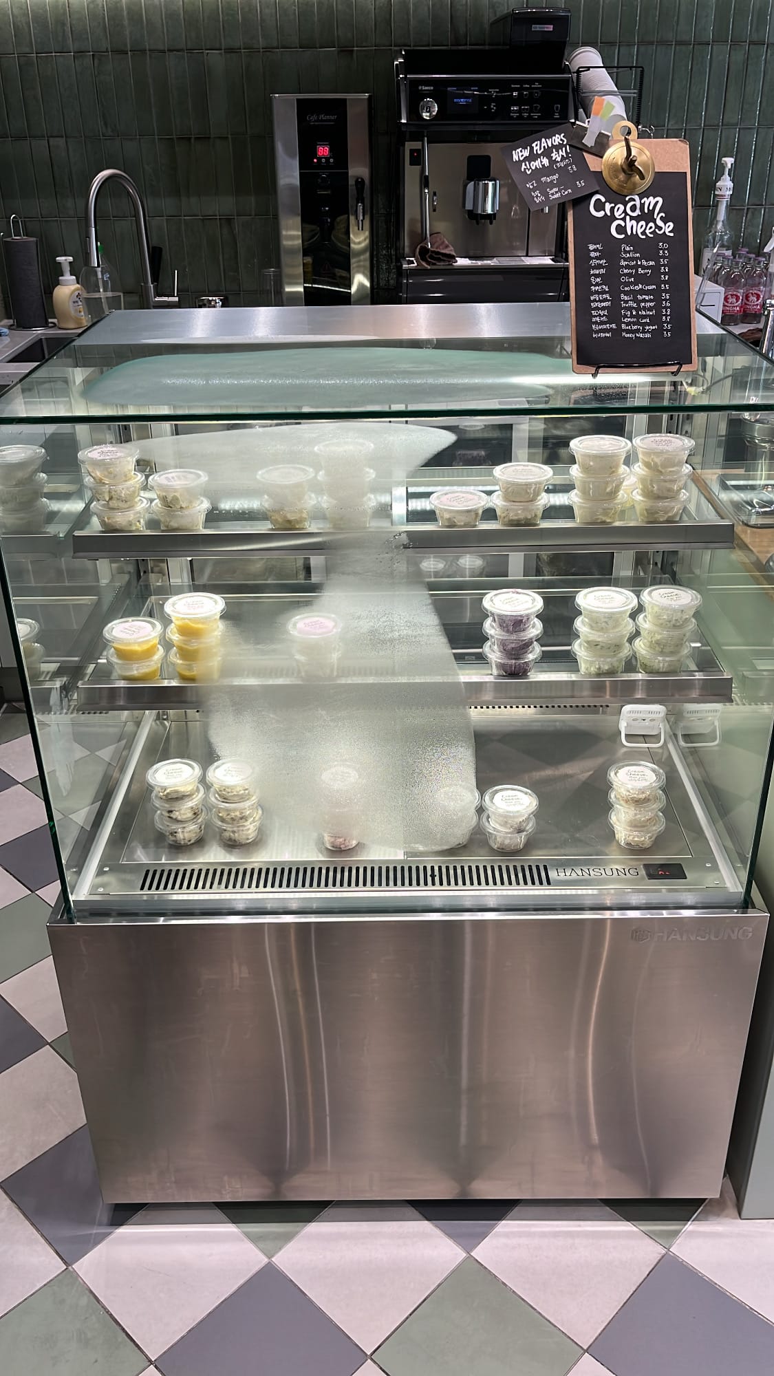 Glass showcase refrigerator filled with various handmade cream cheese containers at Bagel Then You Busan Centum