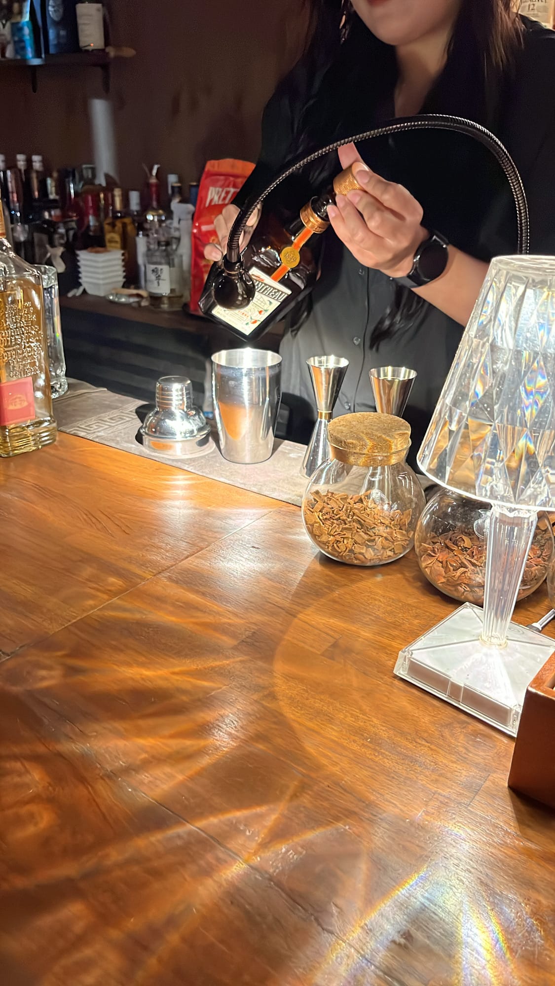 Bartender pouring Cointreau orange liqueur into a cocktail shaker