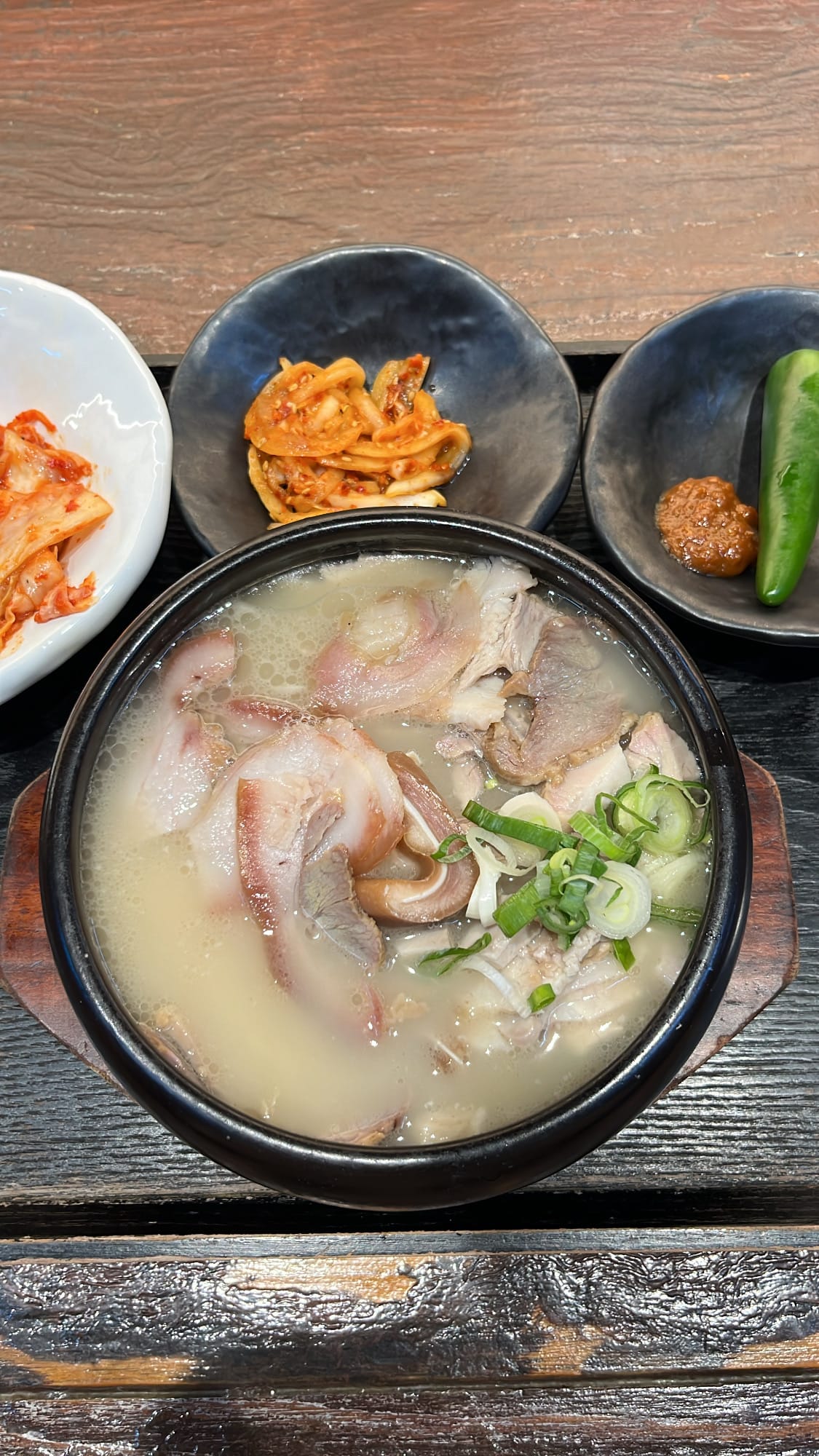 Close-up shot of rich pork belly, head meat slices, and clear broth inside Anmok Busan gukbap bowl