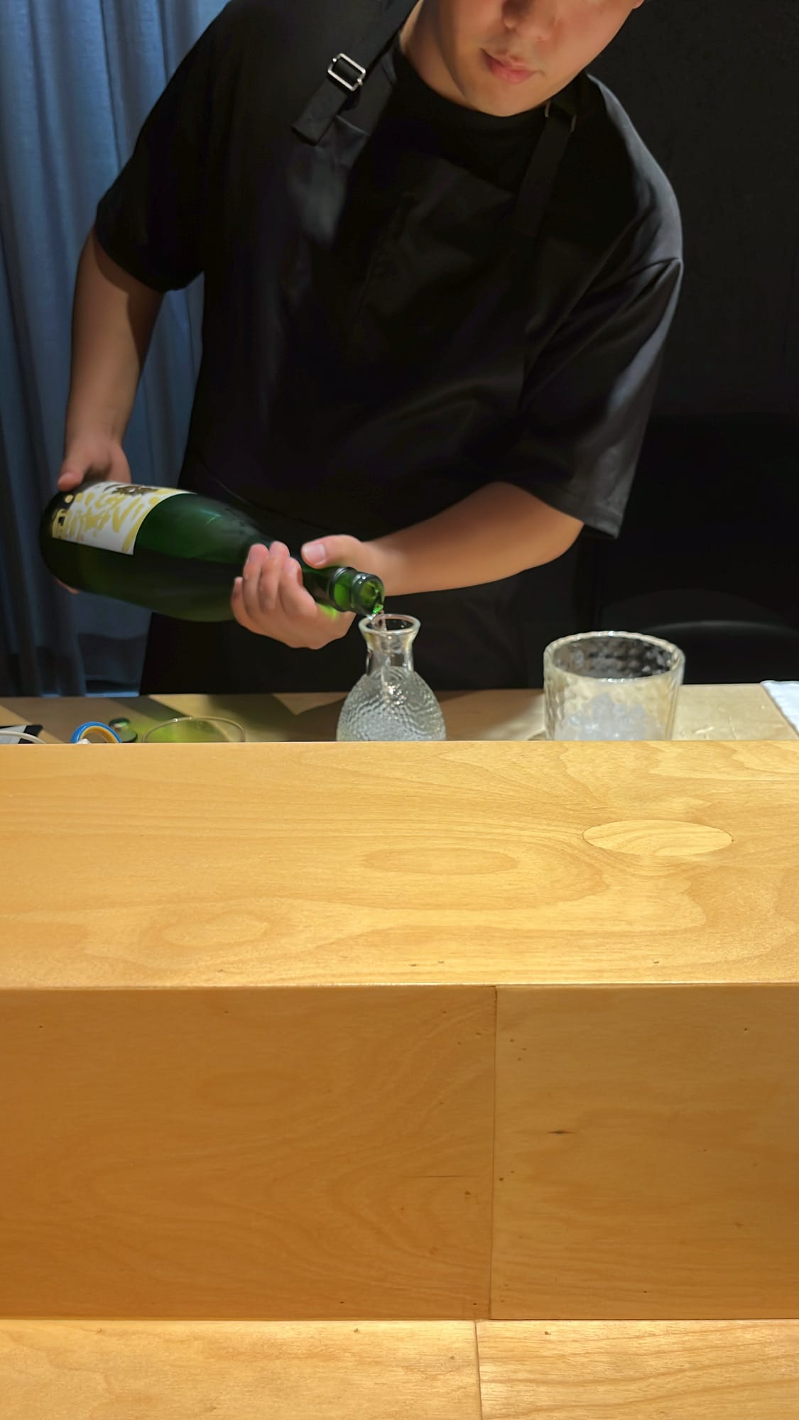 Chef pouring chilled Nanbu Bijin sake into a glass tokkuri at Murasaki Busan