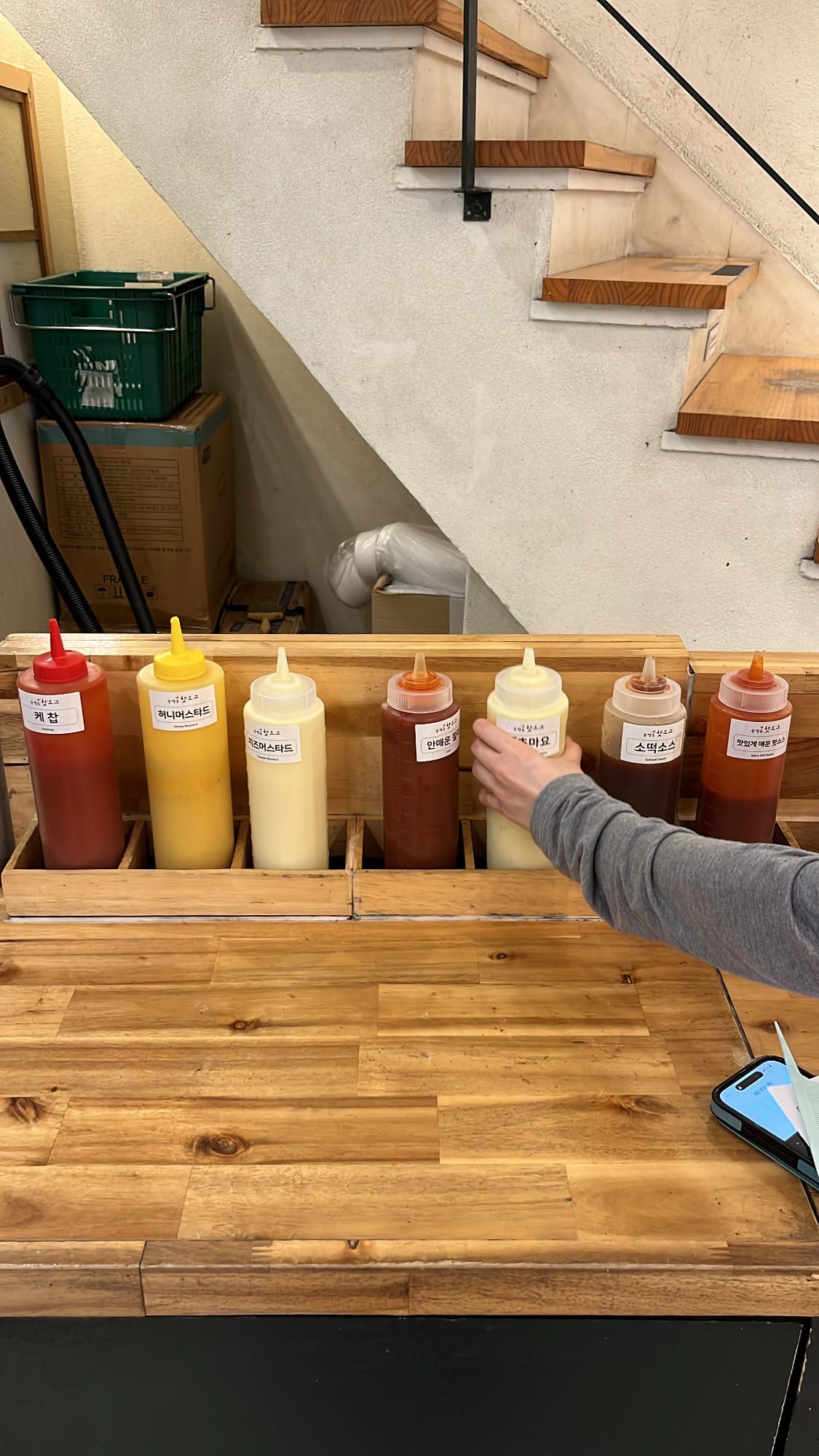 Condiment bar with various sauces at Songjeong Hot Dog Busan