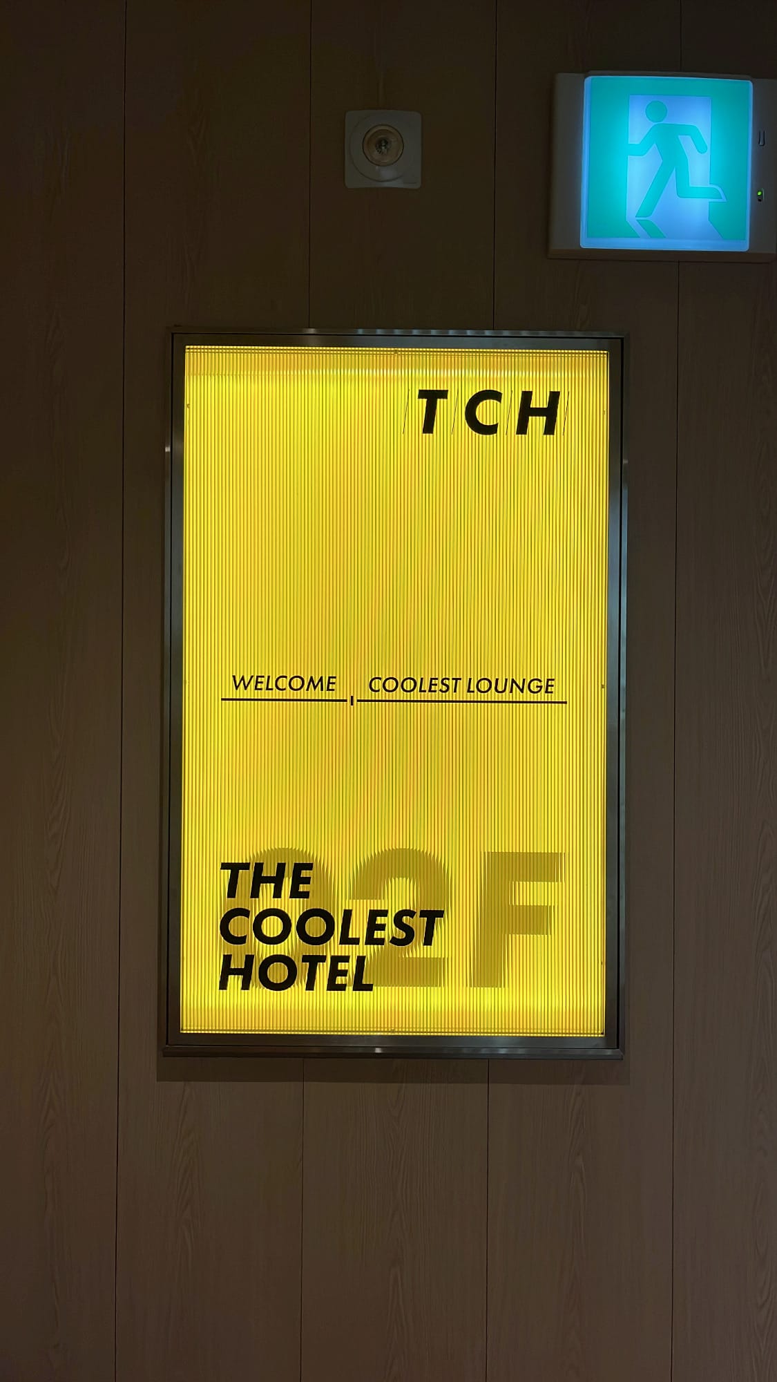 Yellow illuminated floor directory sign for Coolest Lounge at The Coolest Hotel