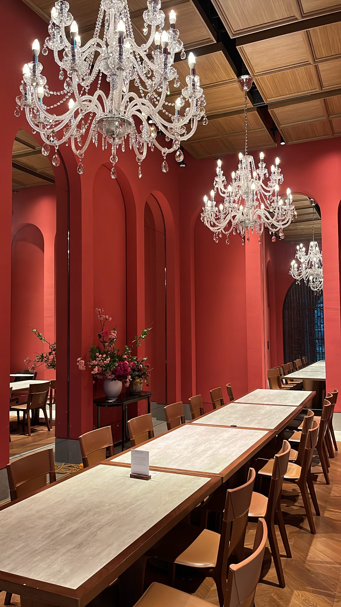 Long banquet table beneath dual crystal chandeliers in an oriental red room at Village de Ananti Lou Busan