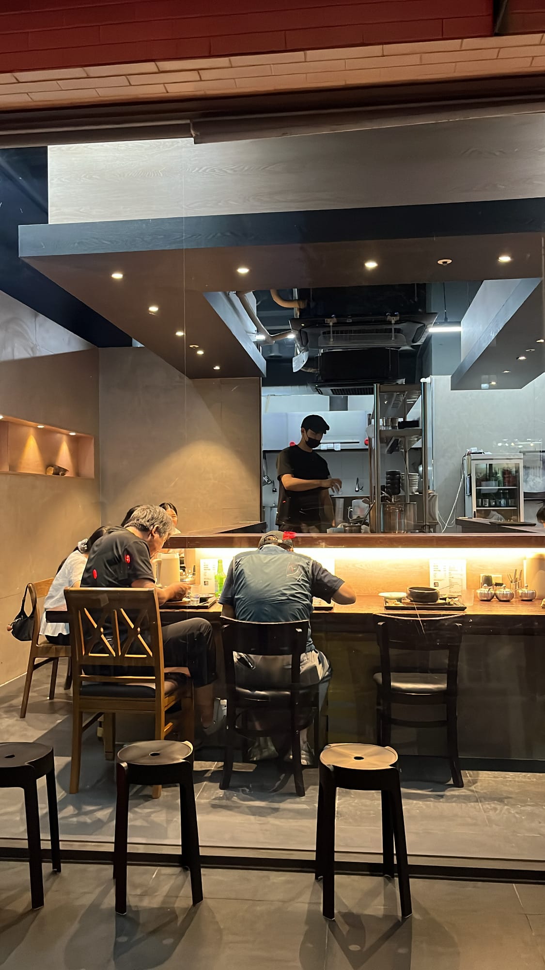 Warmly lit evening dining scene at the open bar counter inside Anmok Busan