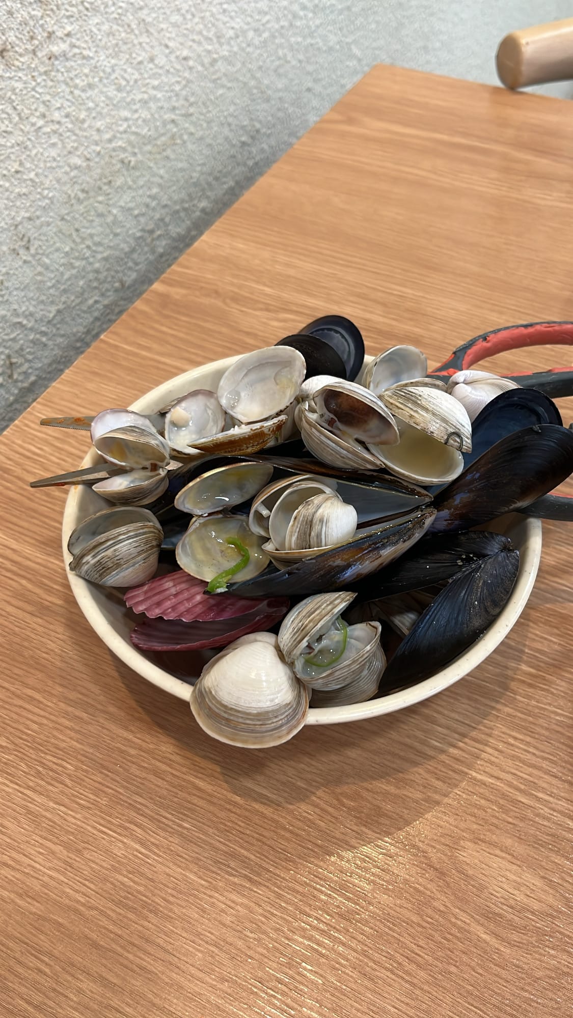 Small metal bowl filled high with discarded clam and mussel shells
