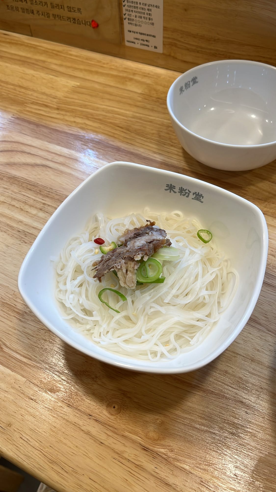 Complimentary extra rice noodles and beef slice served in a clean white bowl at Mifendang Busan