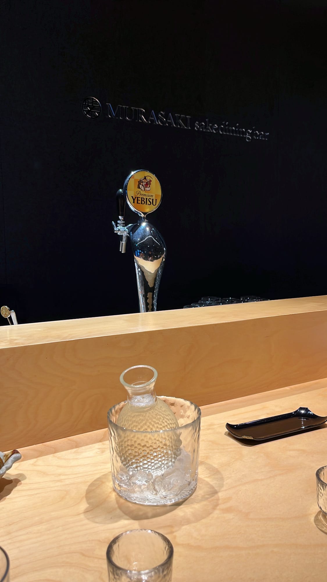 Iced sake carafe and matching glass cups on the counter at Murasaki Busan