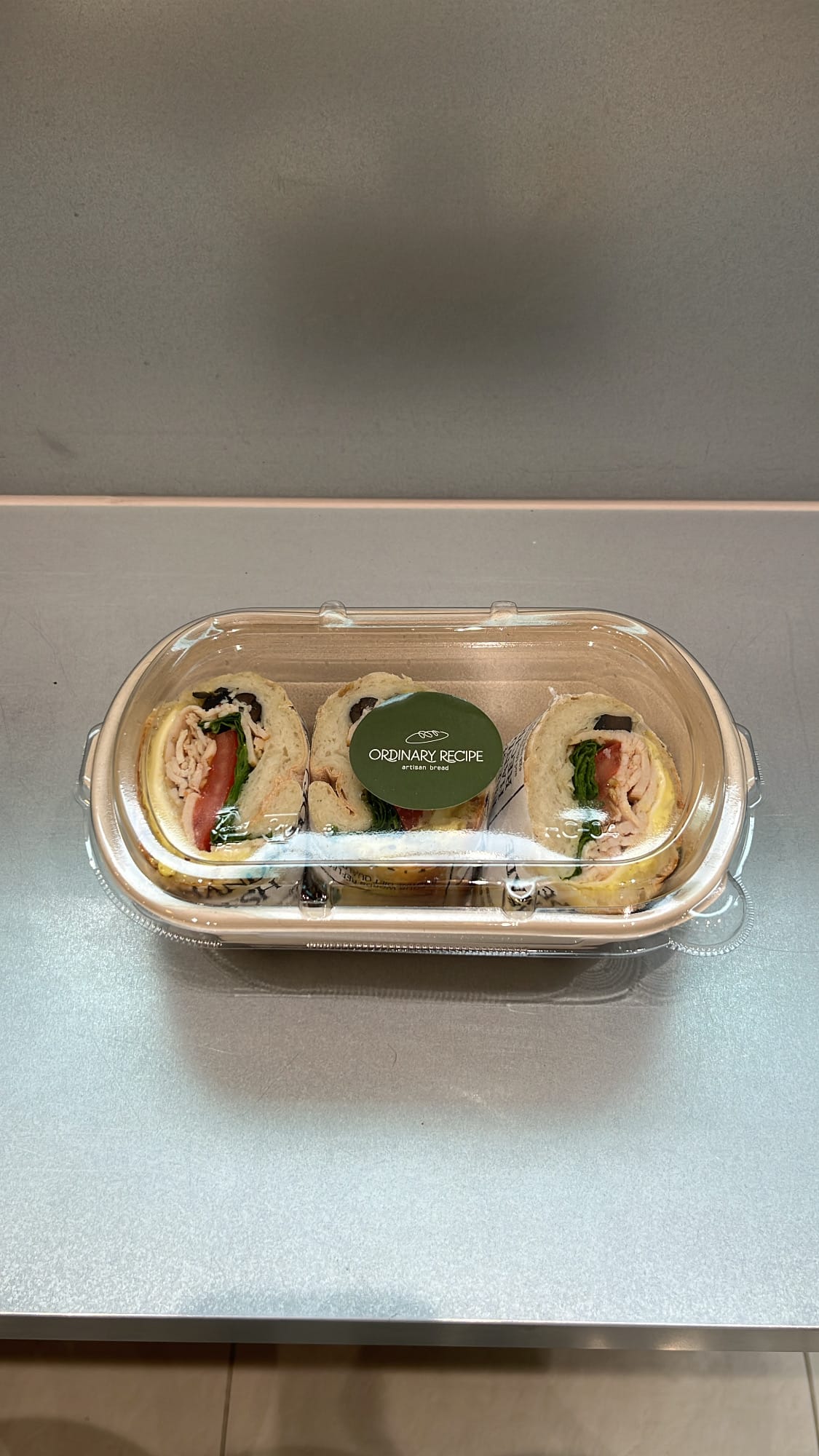 Takeout container containing sliced chicken ciabatta sandwich from Ordinary Recipe Centum