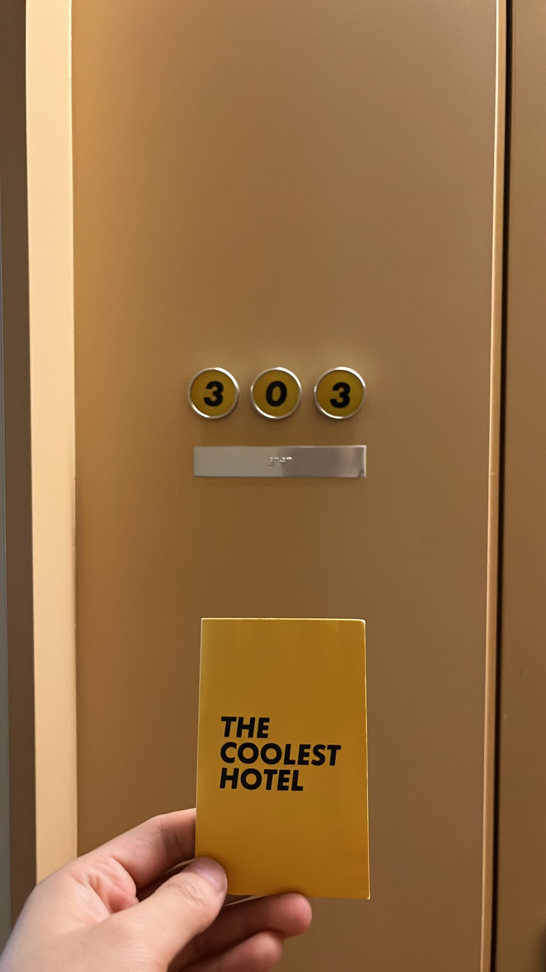 Room 303 keycard held in front of the room door at The Coolest Hotel