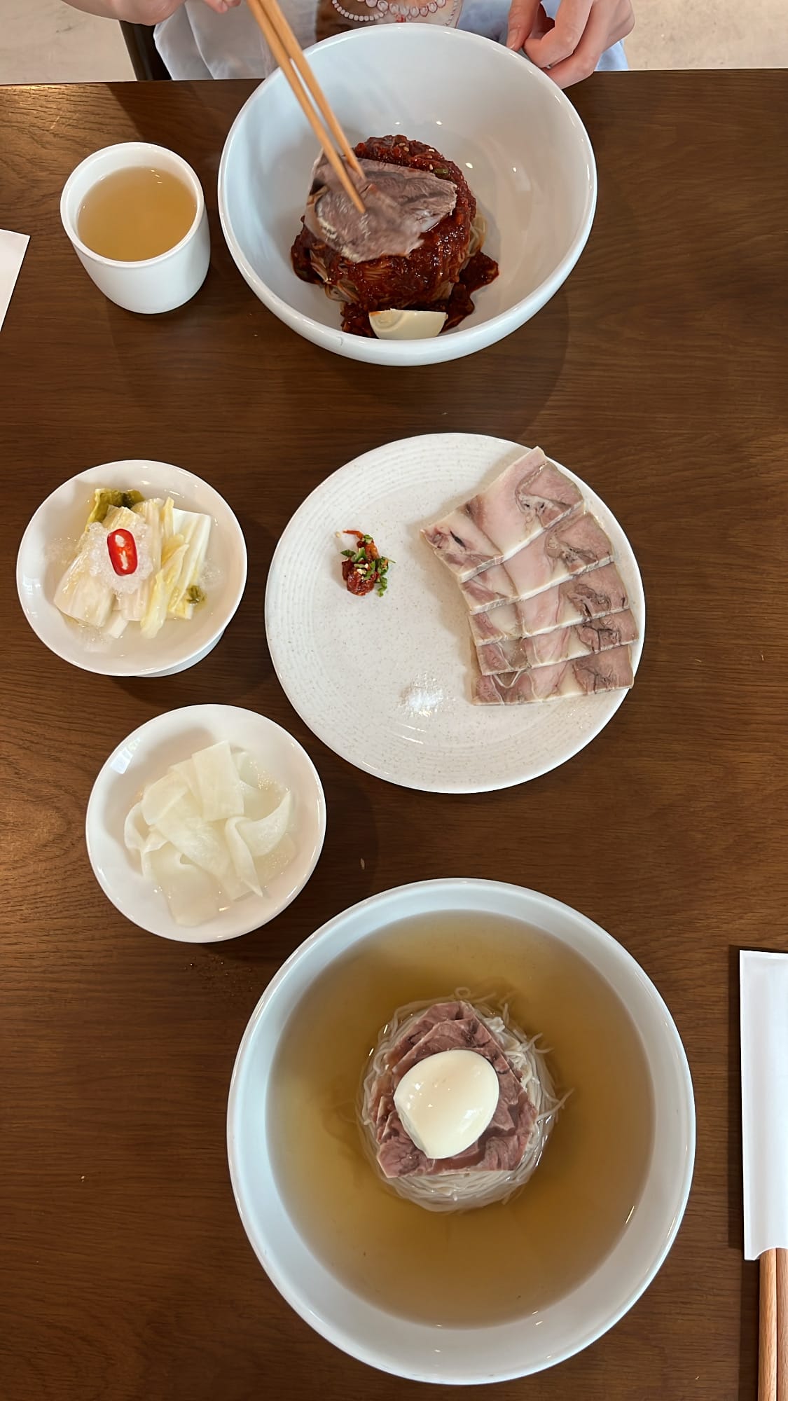 Full table spread with Pyongyang naengmyeon and pork slices at Yangkyungoak Busan