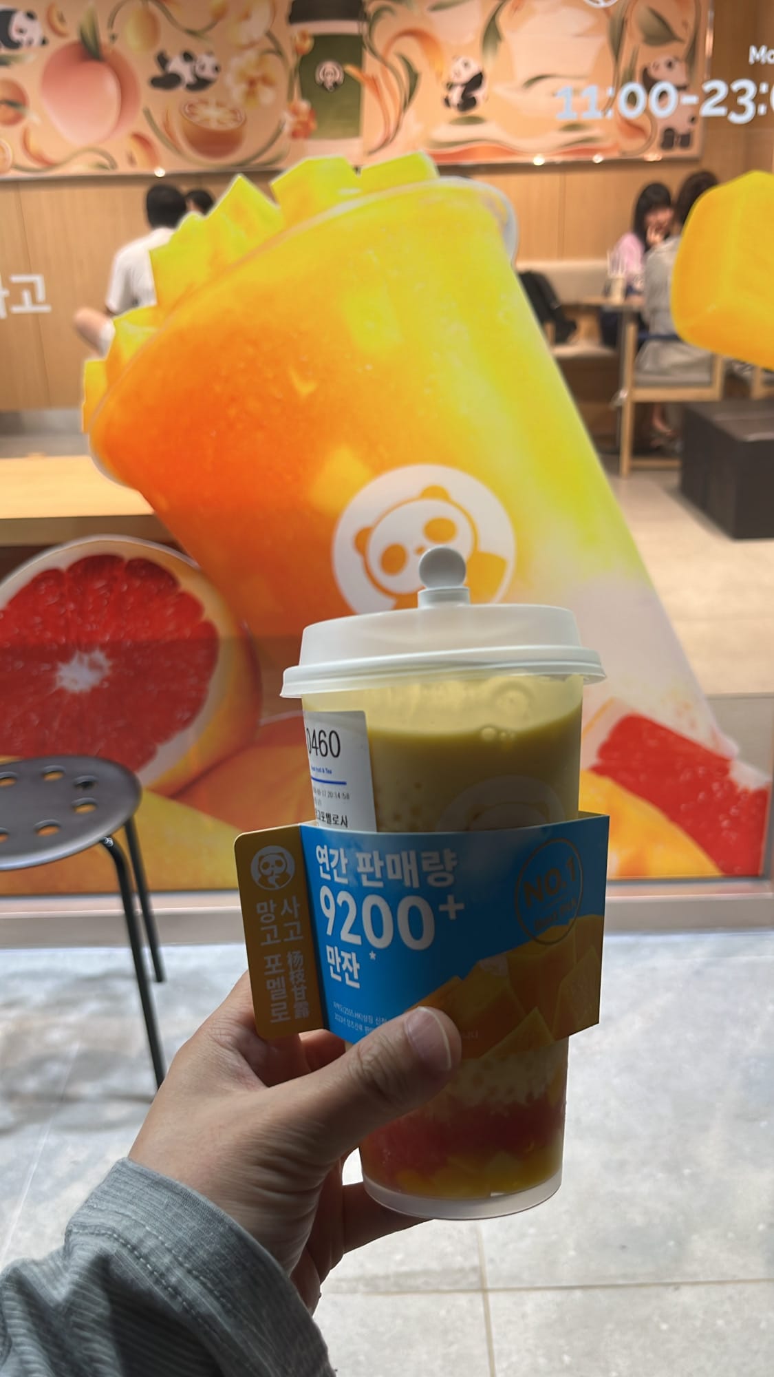 Customer holding up a Mango Pomelo Sago cup inside ChaPanda Busan Centum