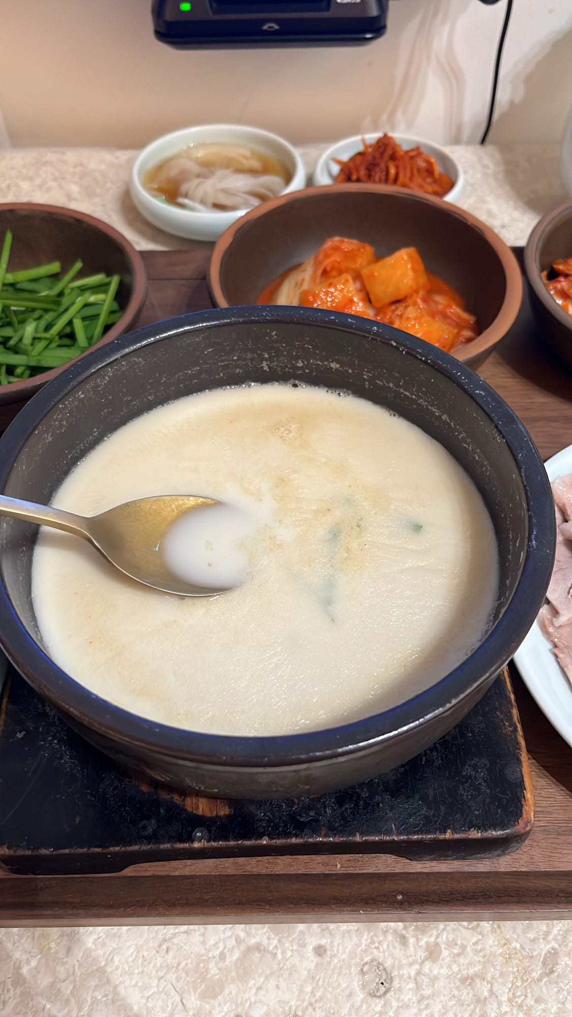 Spoon scooping the creamy and savory pork bone broth at Geodae Dwaeji Gukbap Busan