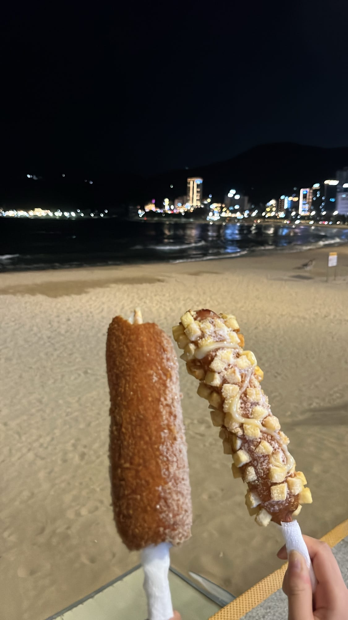 Eating crispy corn dogs with an ocean view at Songjeong Beach