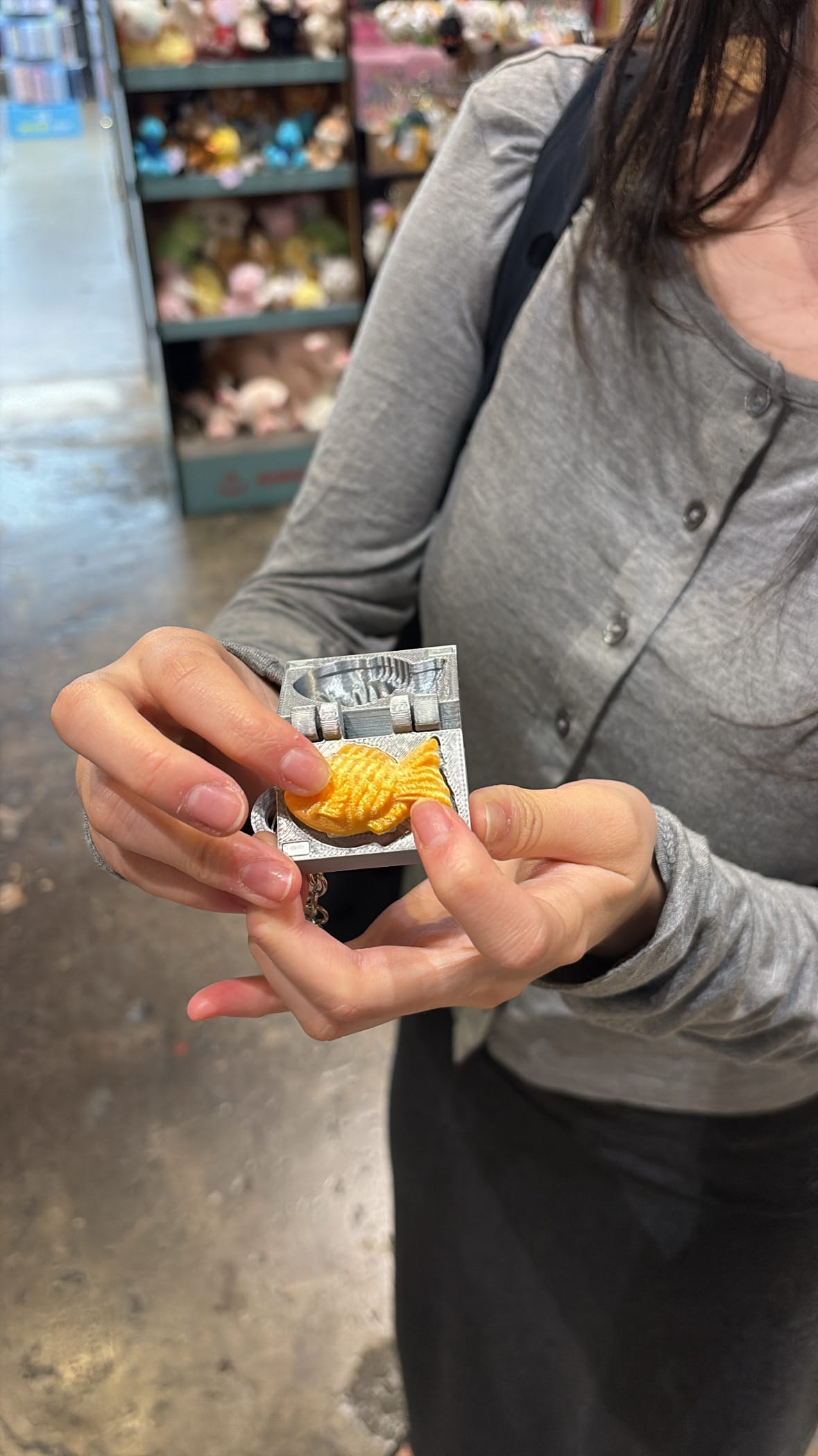 Hand holding a miniature bungeoppang waffle mold keycap at YES24 Busan