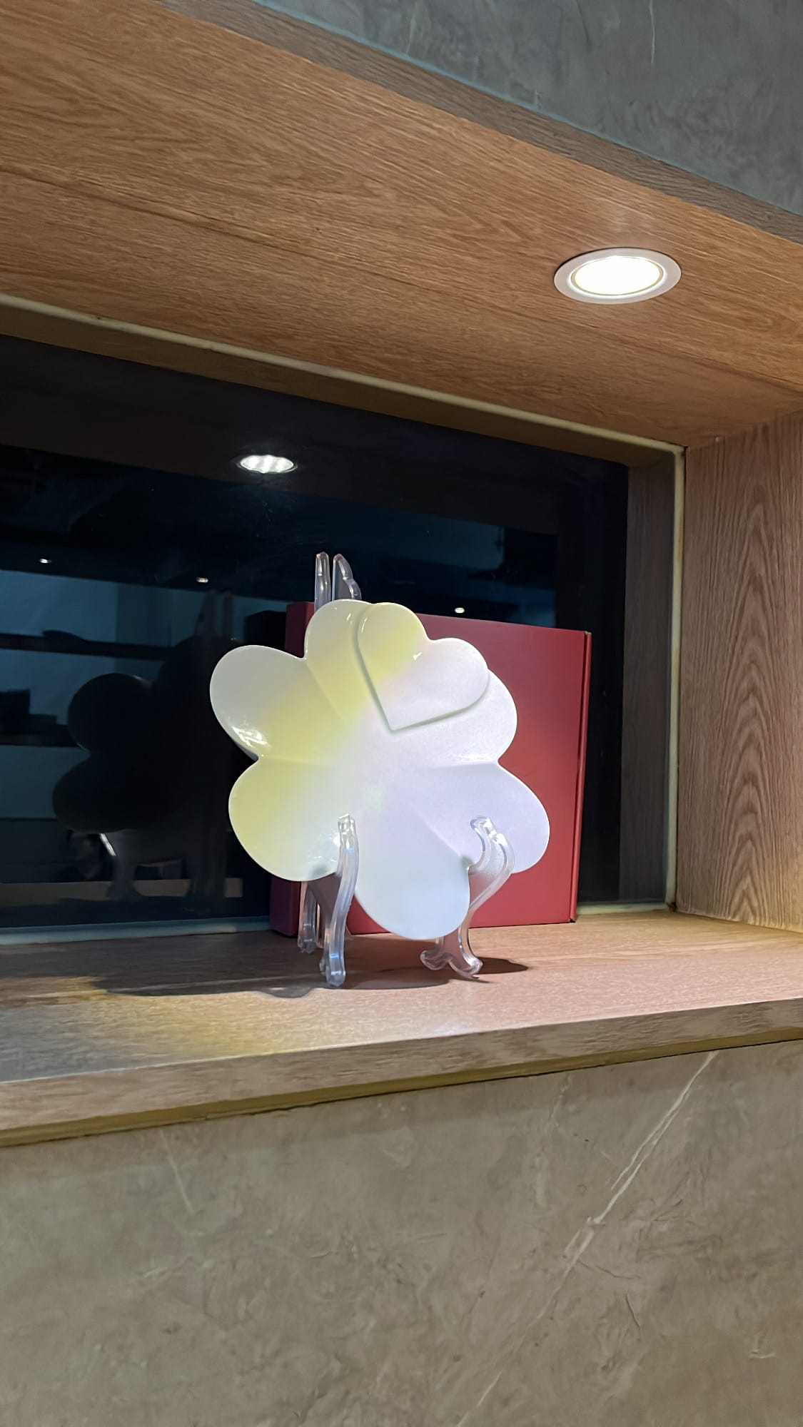 Artistic clover-shaped ceramic display plate set within the wooden interior shelf of Anmok Busan