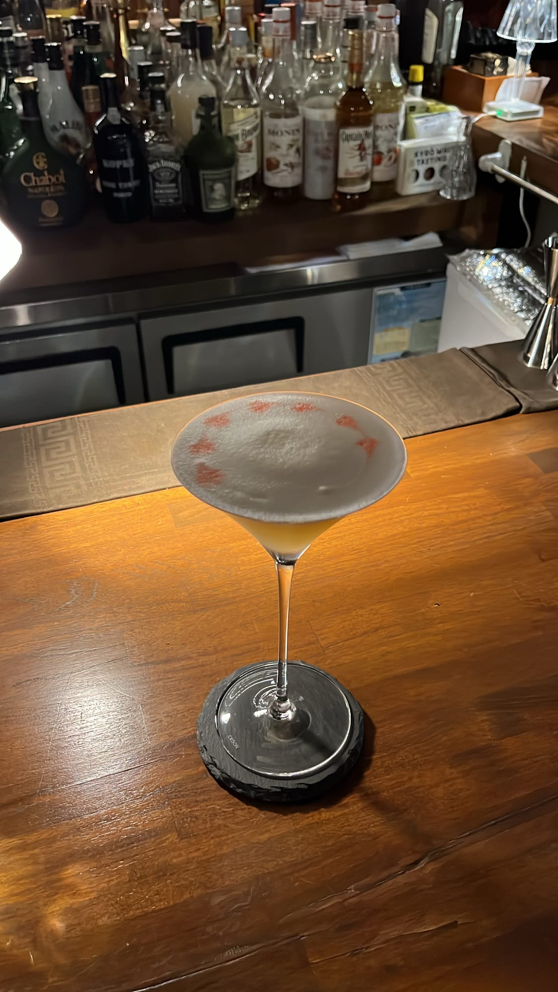 Elegant sour cocktail garnished with delicate red bitters drops