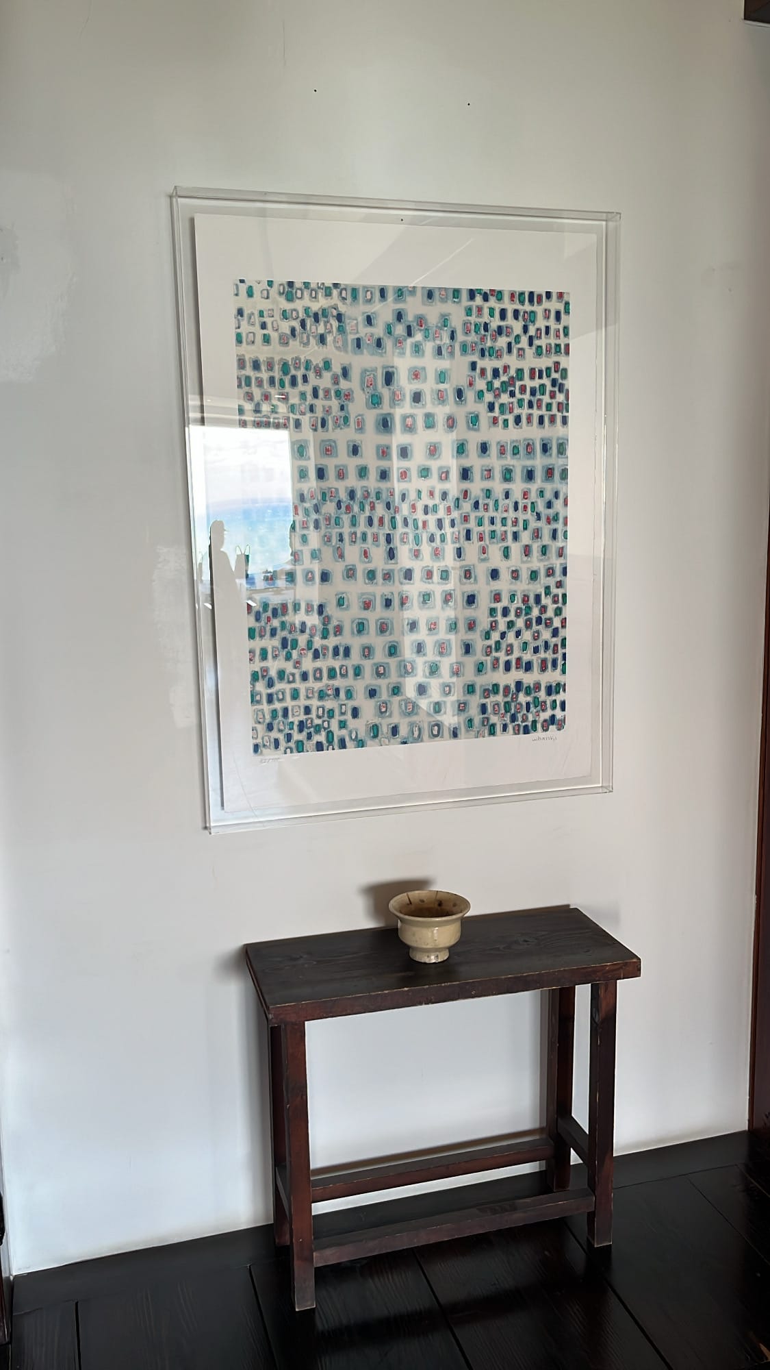Colorful patterned textile artwork displayed above a small wooden console table