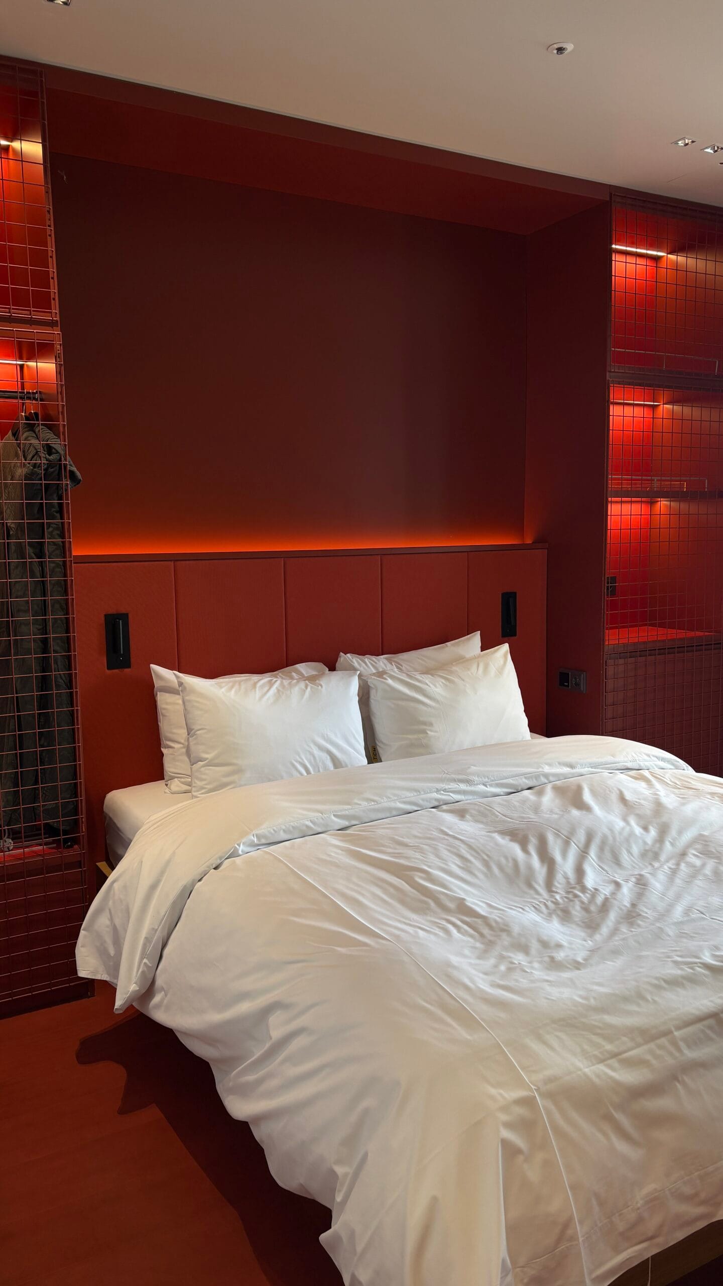 Plush double bed with crimson headboard and mood lighting at The Coolest Hotel