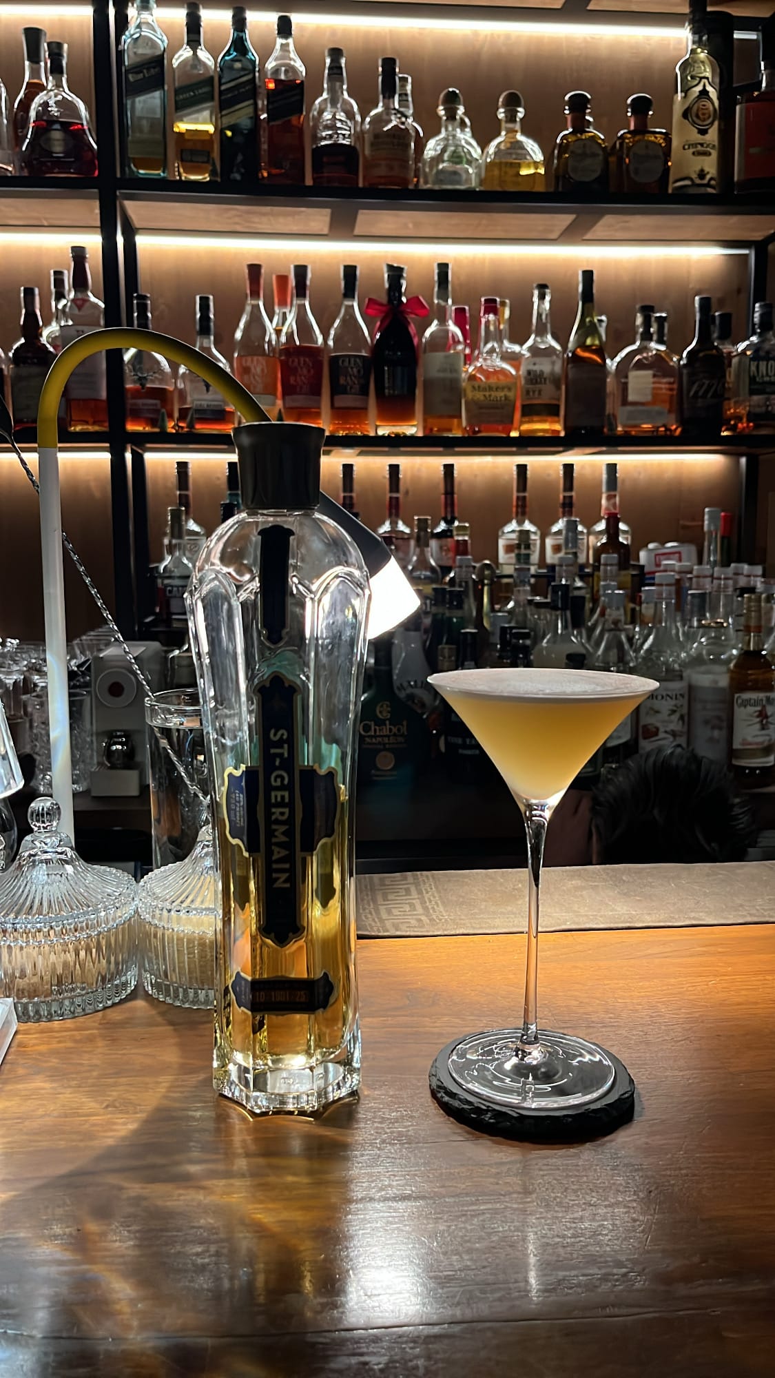 Tall St-Germain bottle placed next to elegant coupe cocktail