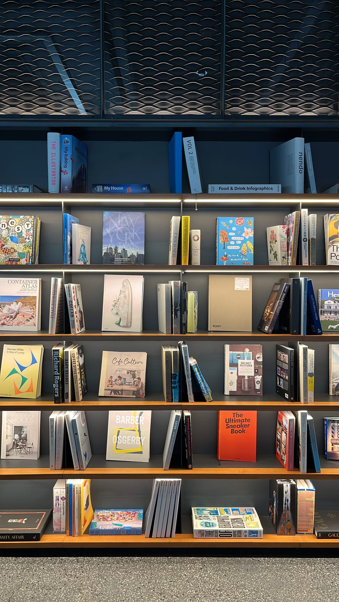 Warmly lit design bookshelf display wall inside Hyundai Motorstudio Busan