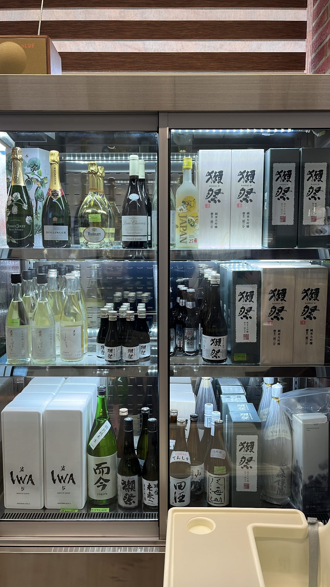 Glass beverage refrigerator stocked with chilled sake, champagne, and Japanese liquor at Unaju Busan