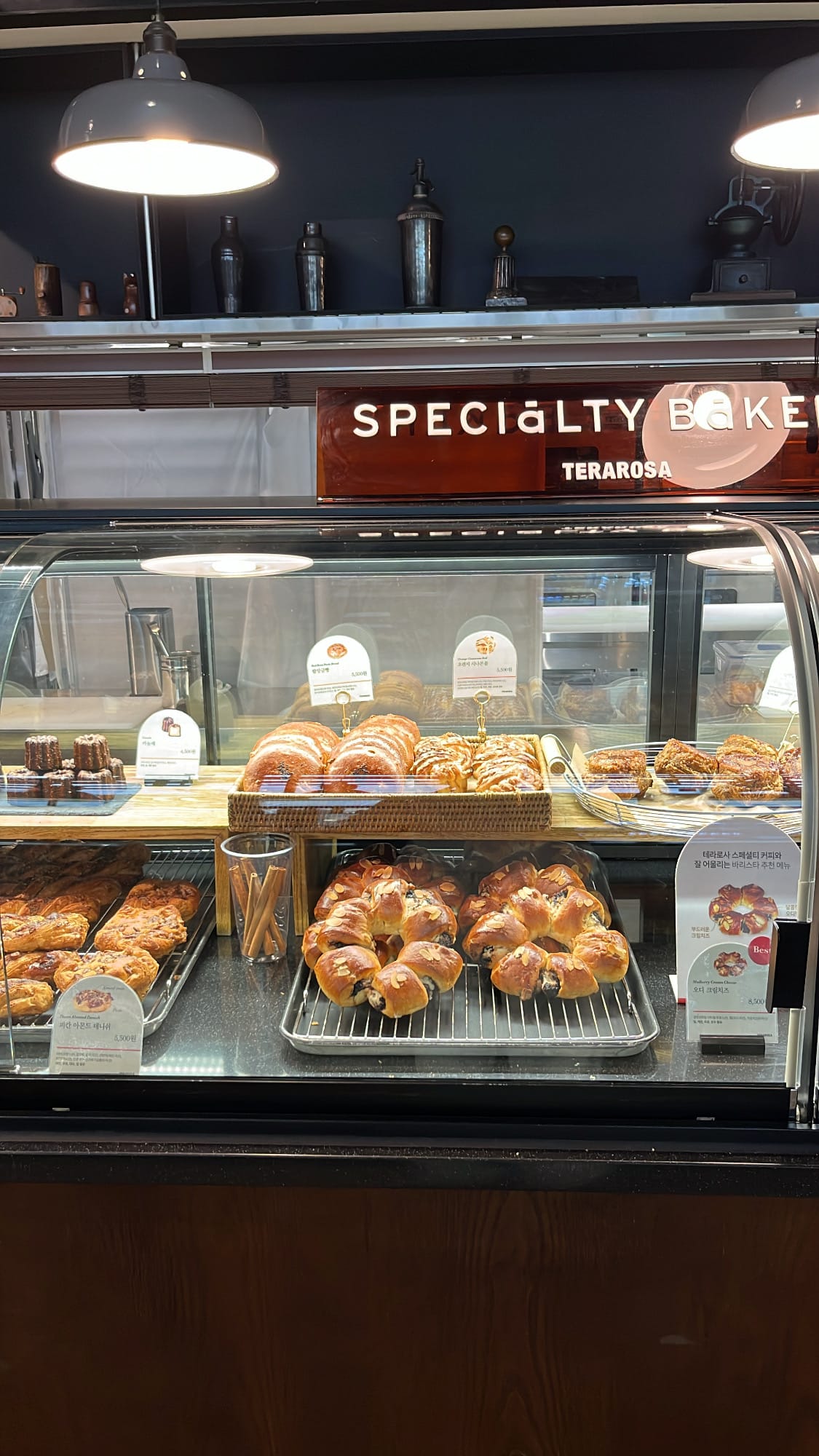 Fresh artisan breads, rolls, and caneles arranged inside bakery showcase